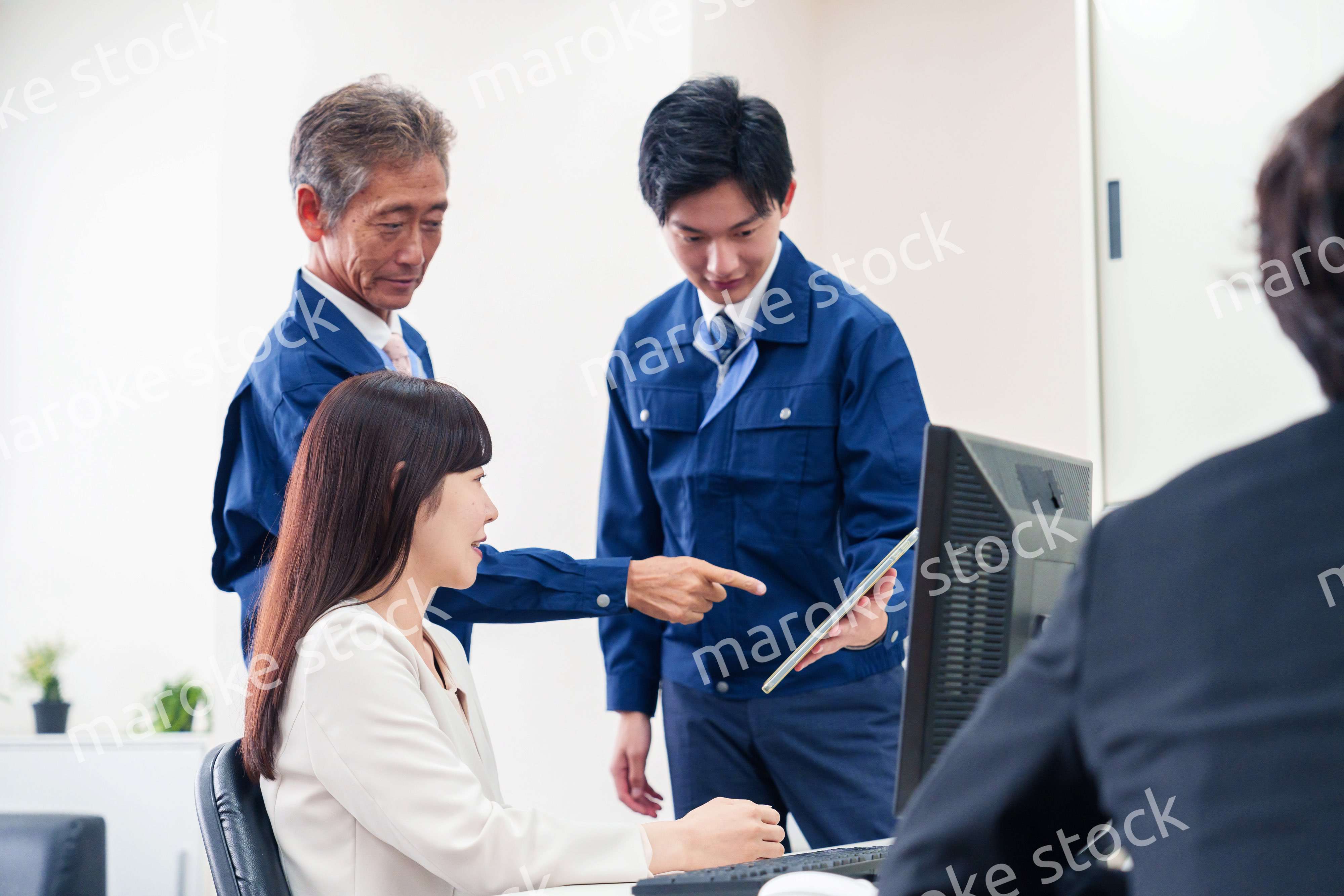 オフィスで話す作業服の人とスーツの女性