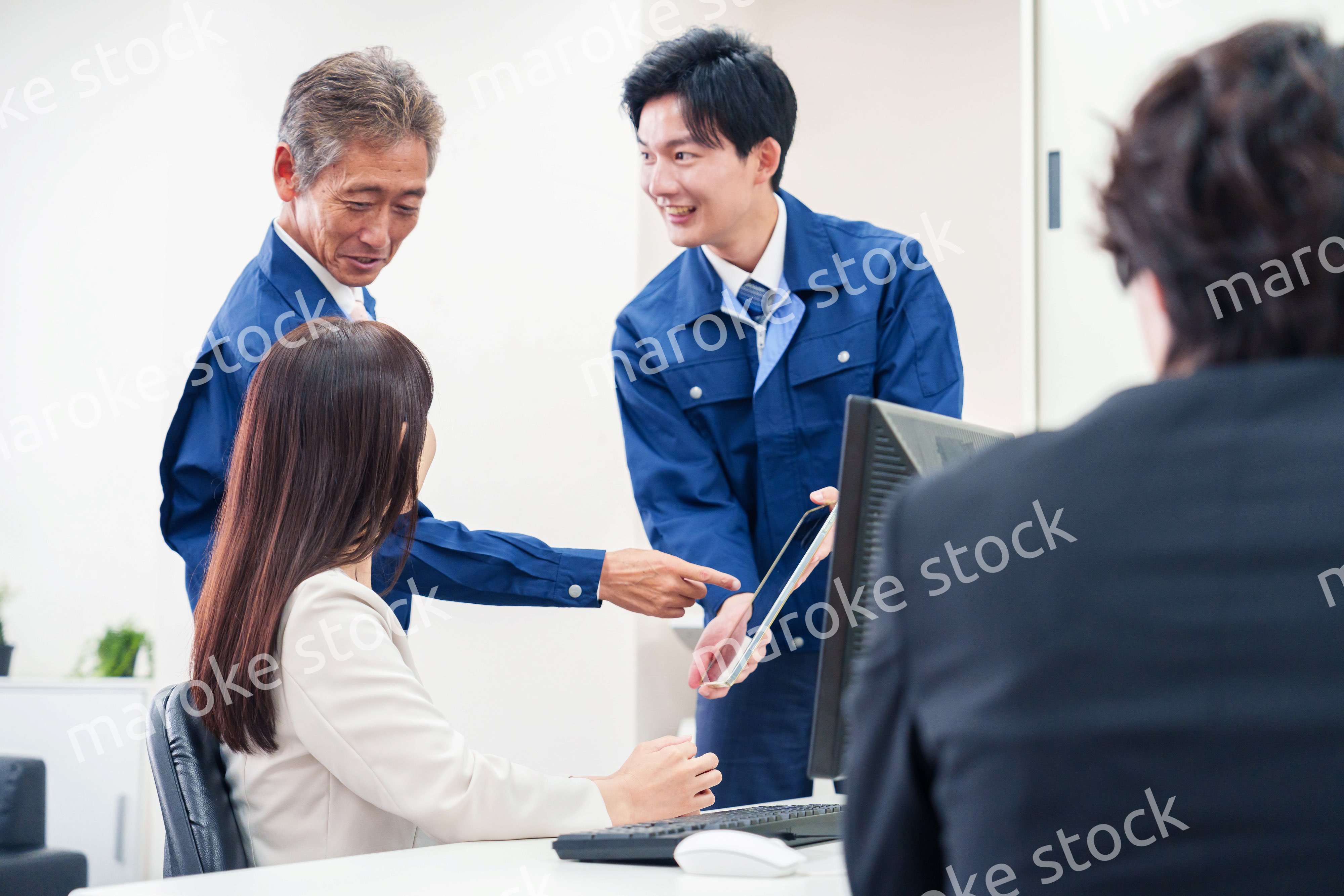 オフィスで話す作業服の人とスーツの女性