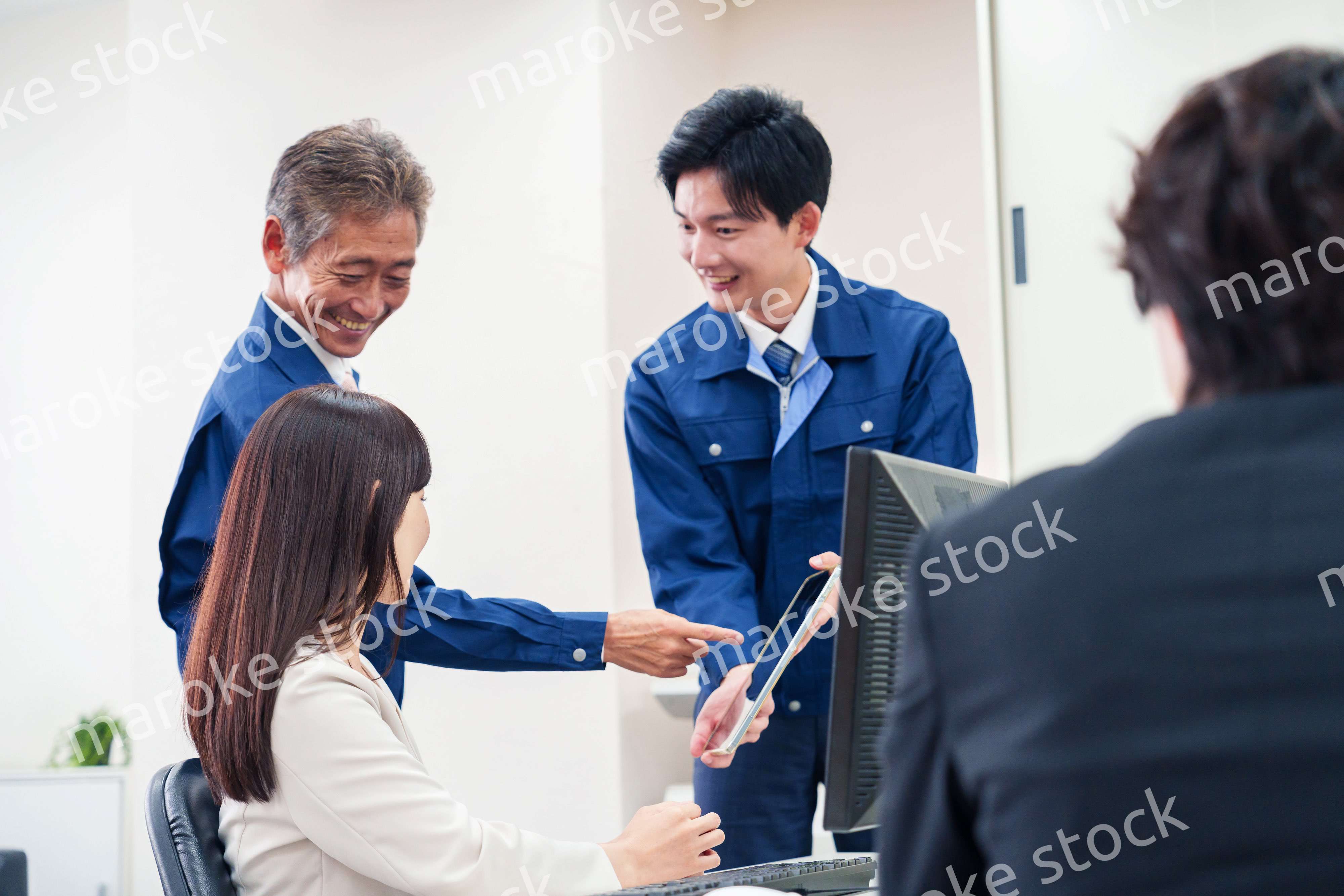 オフィスで話す作業服の人とスーツの女性