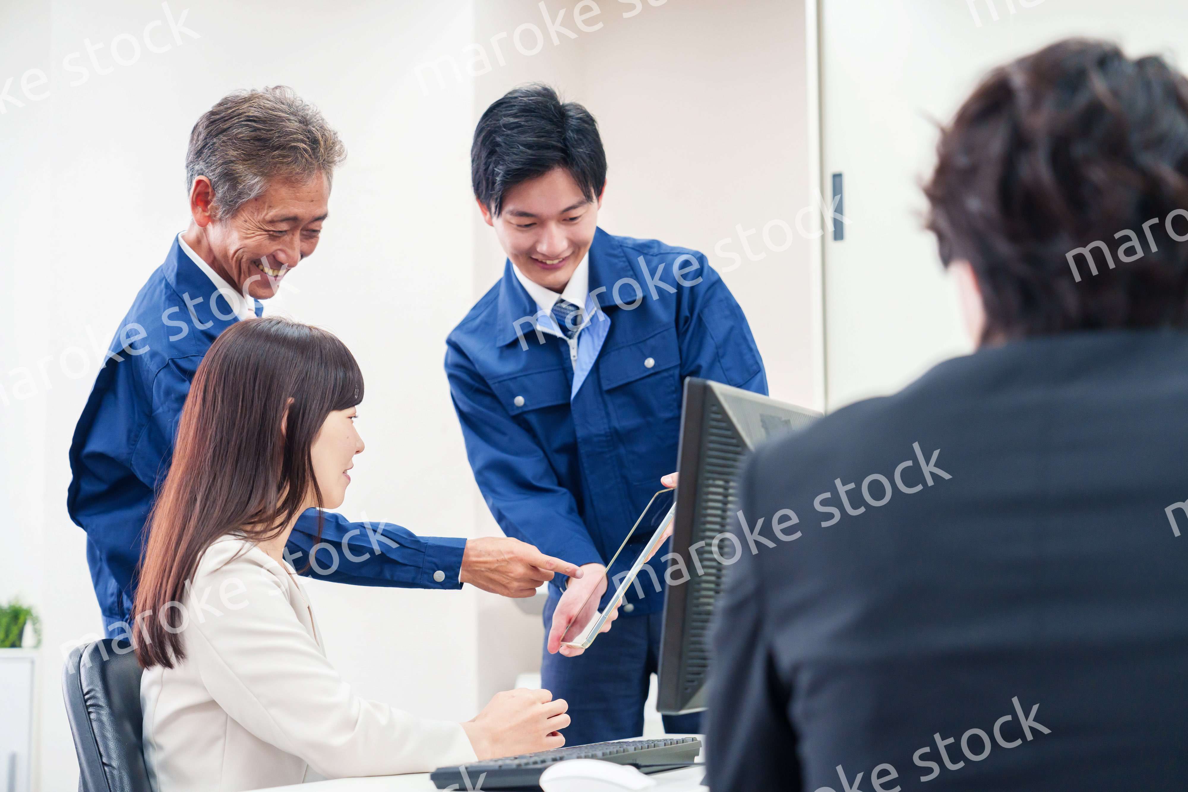 オフィスで話す作業服の人とスーツの女性