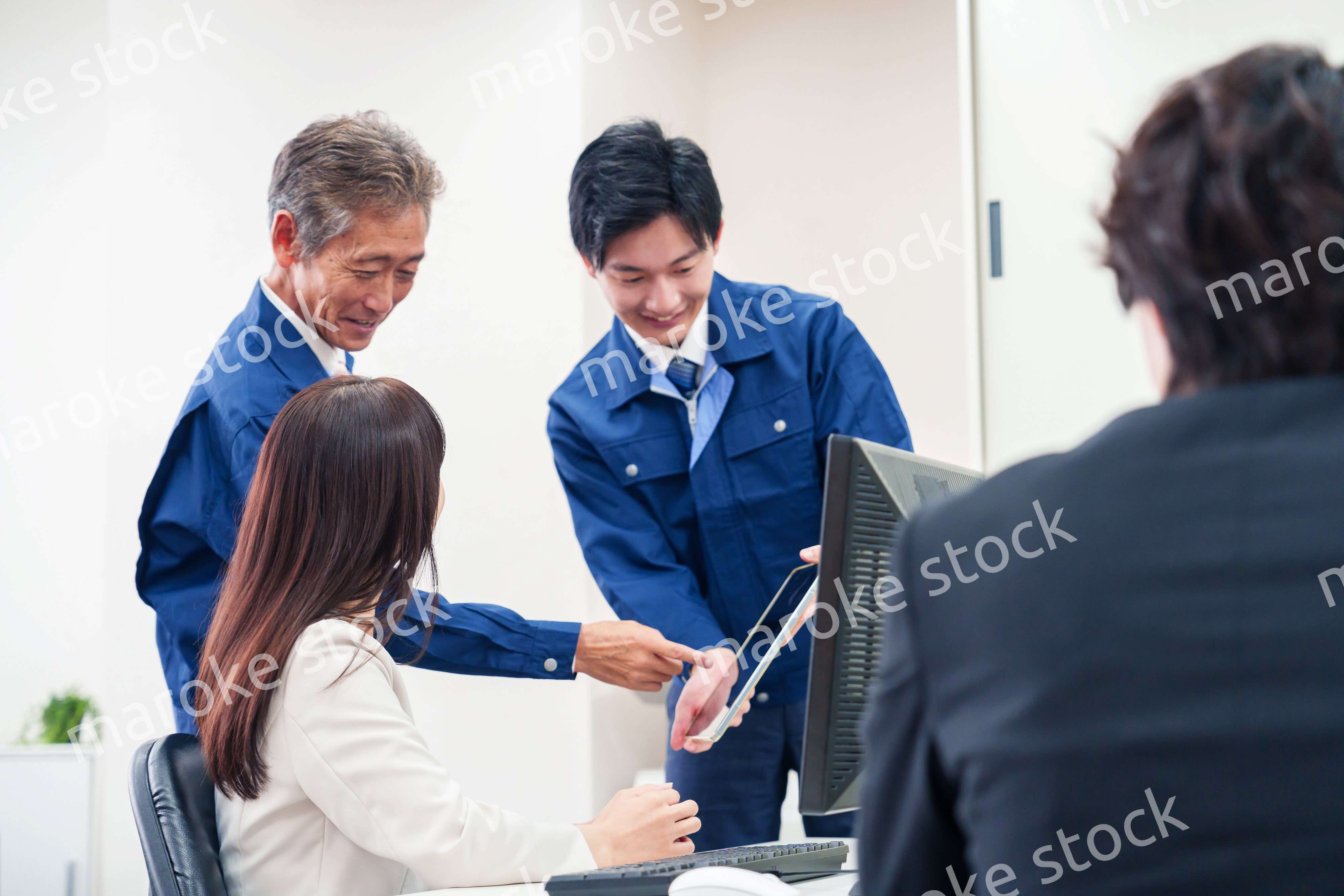 オフィスで話す作業服の人とスーツの女性