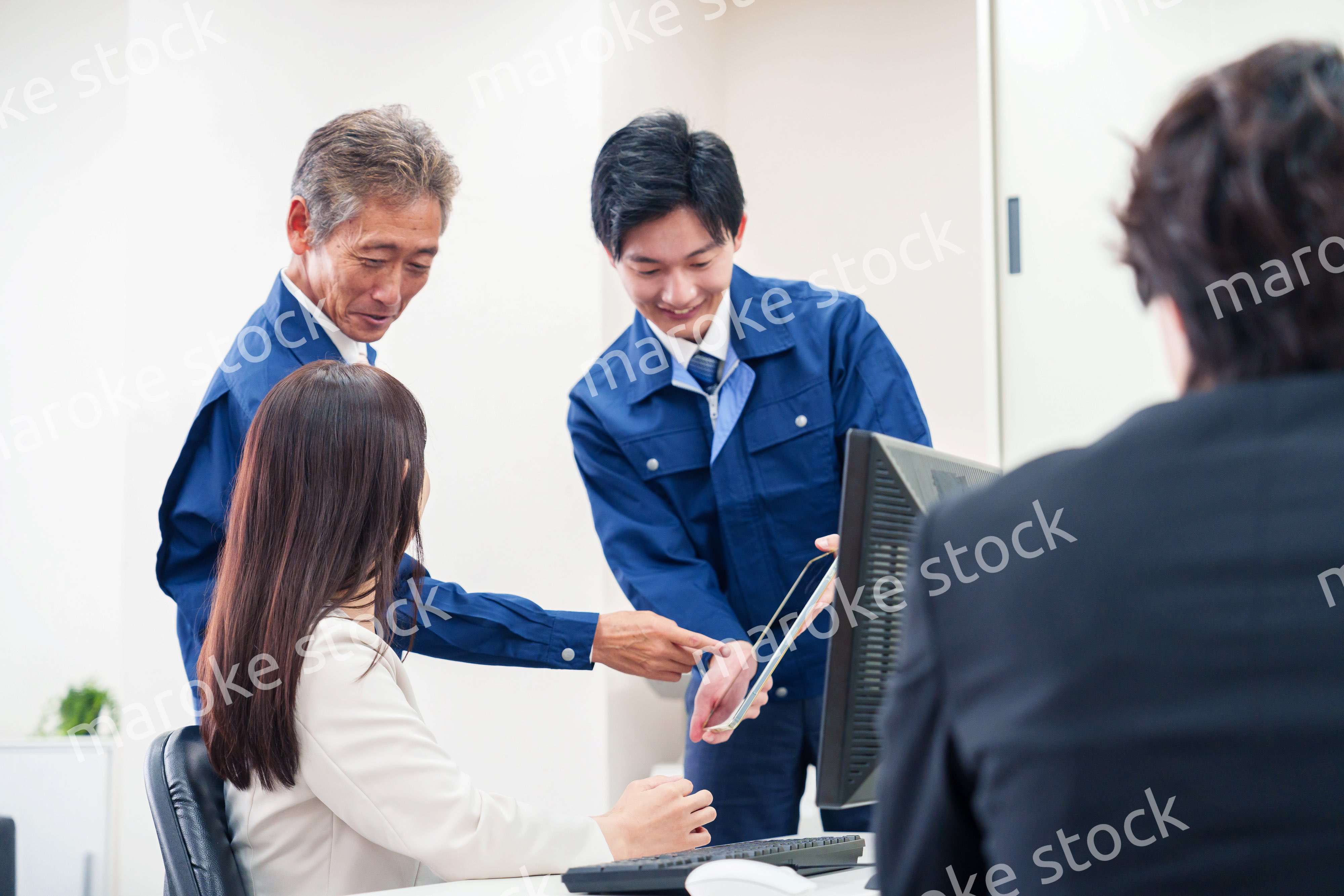 オフィスで話す作業服の人とスーツの女性