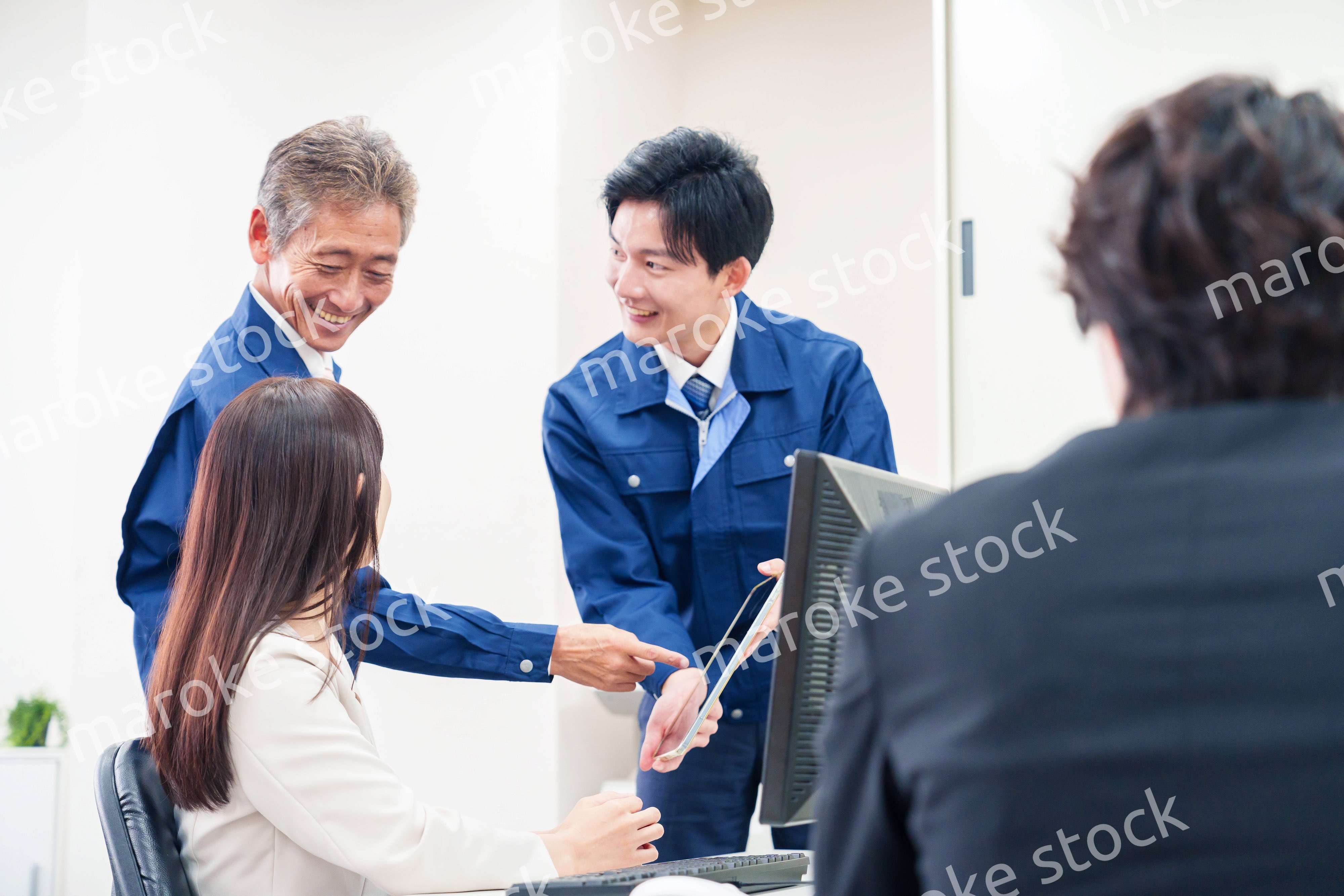 オフィスで話す作業服の人とスーツの女性