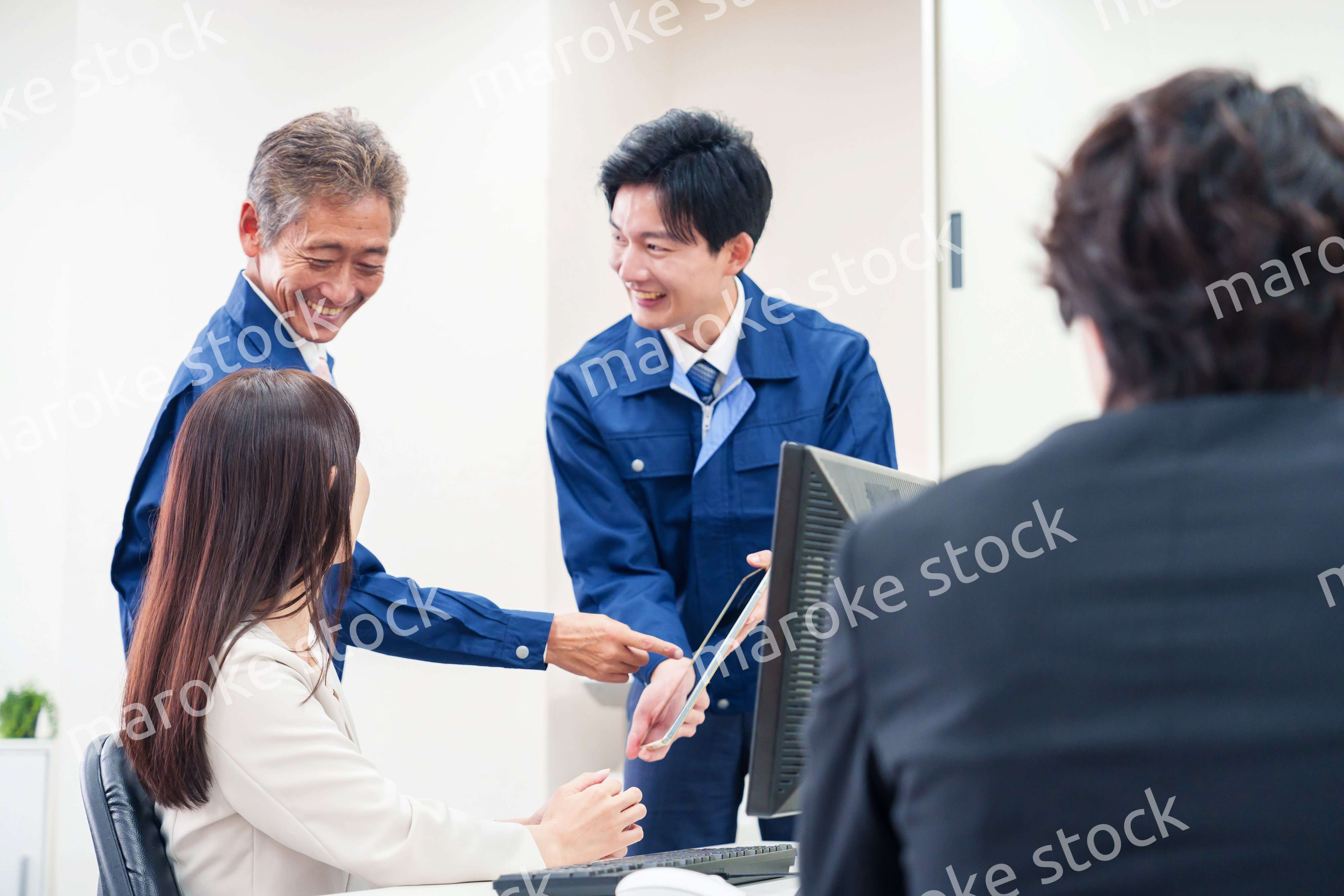 オフィスで話す作業服の人とスーツの女性