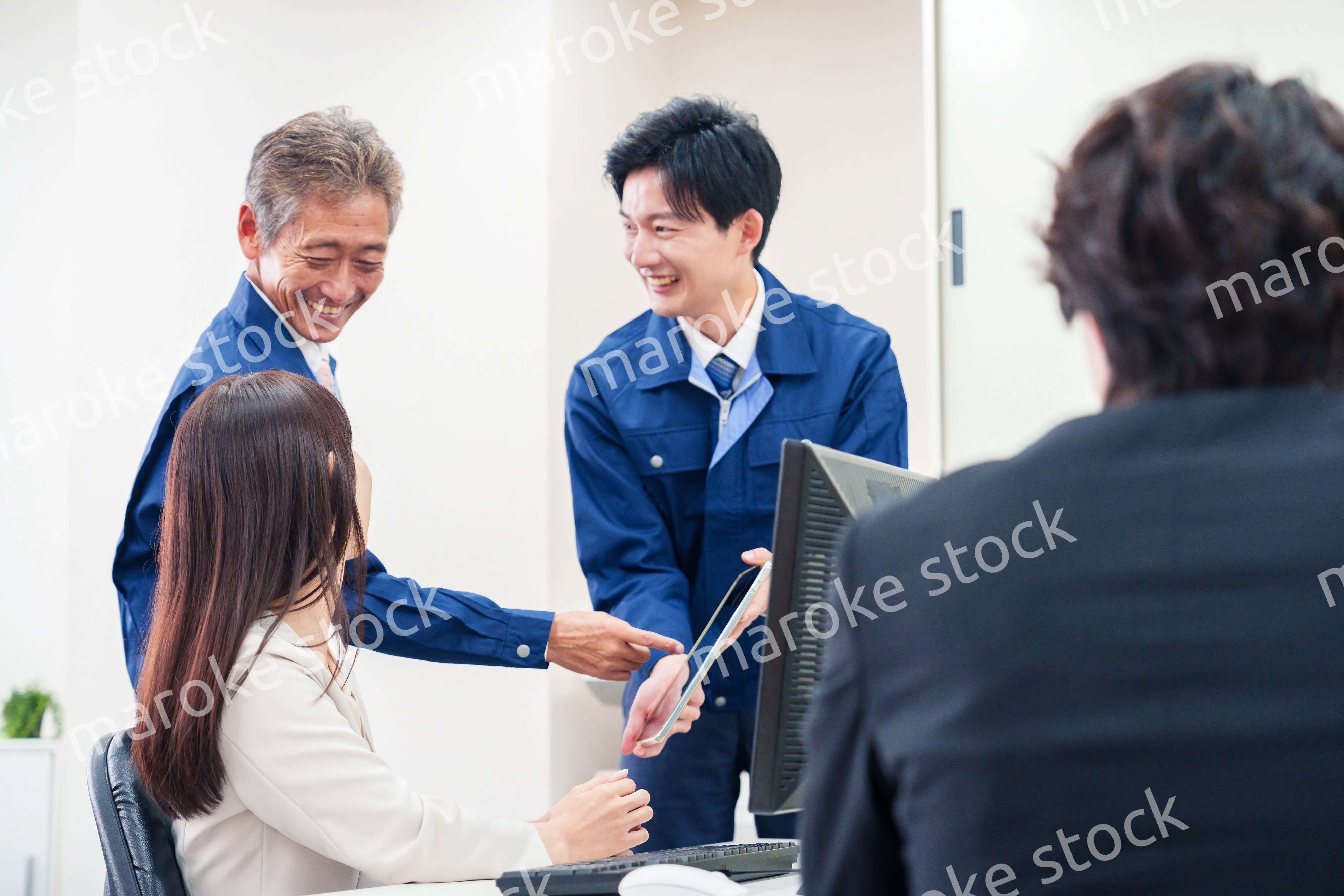 オフィスで話す作業服の人とスーツの女性