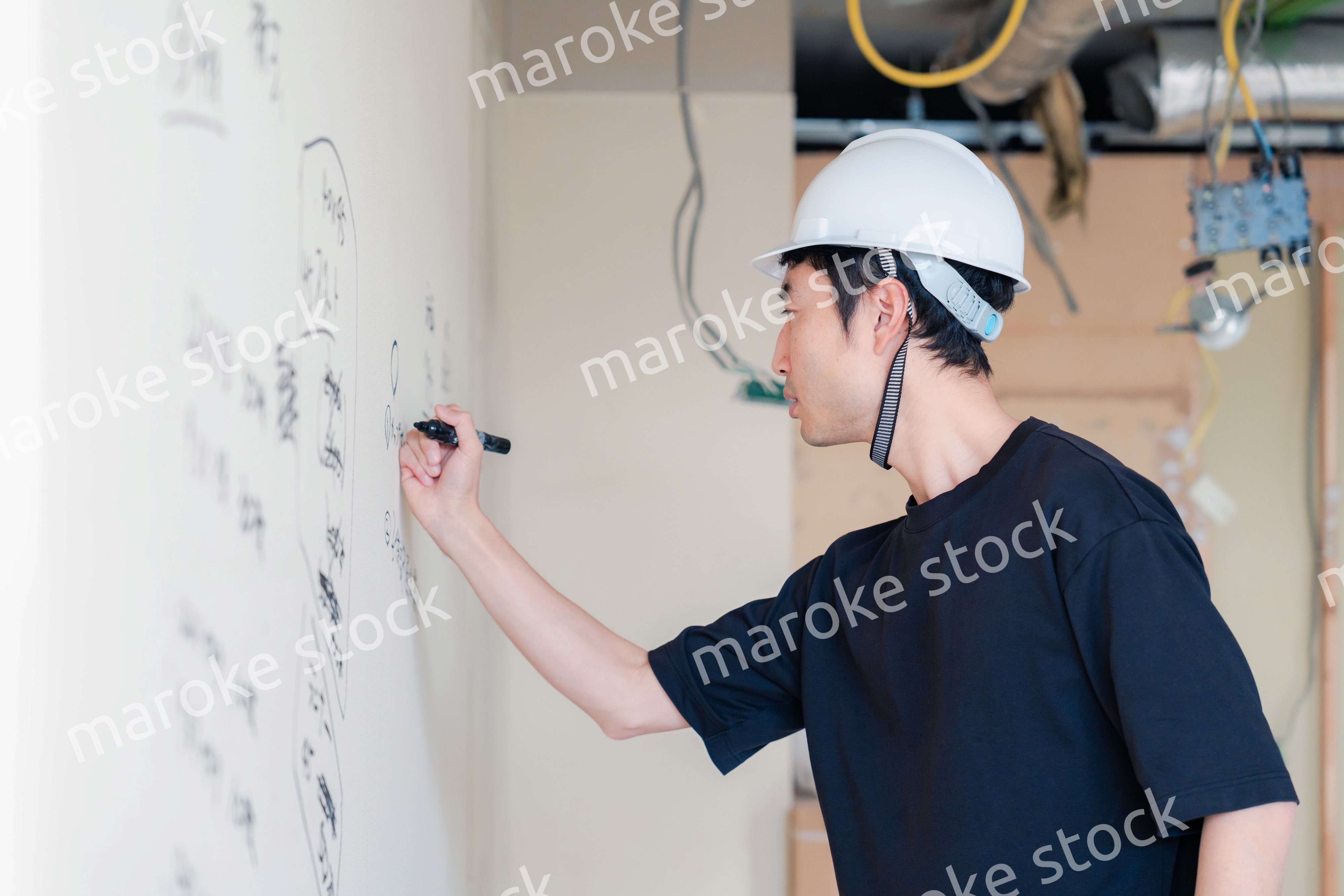 施工中の壁にメモを取る大工さん
