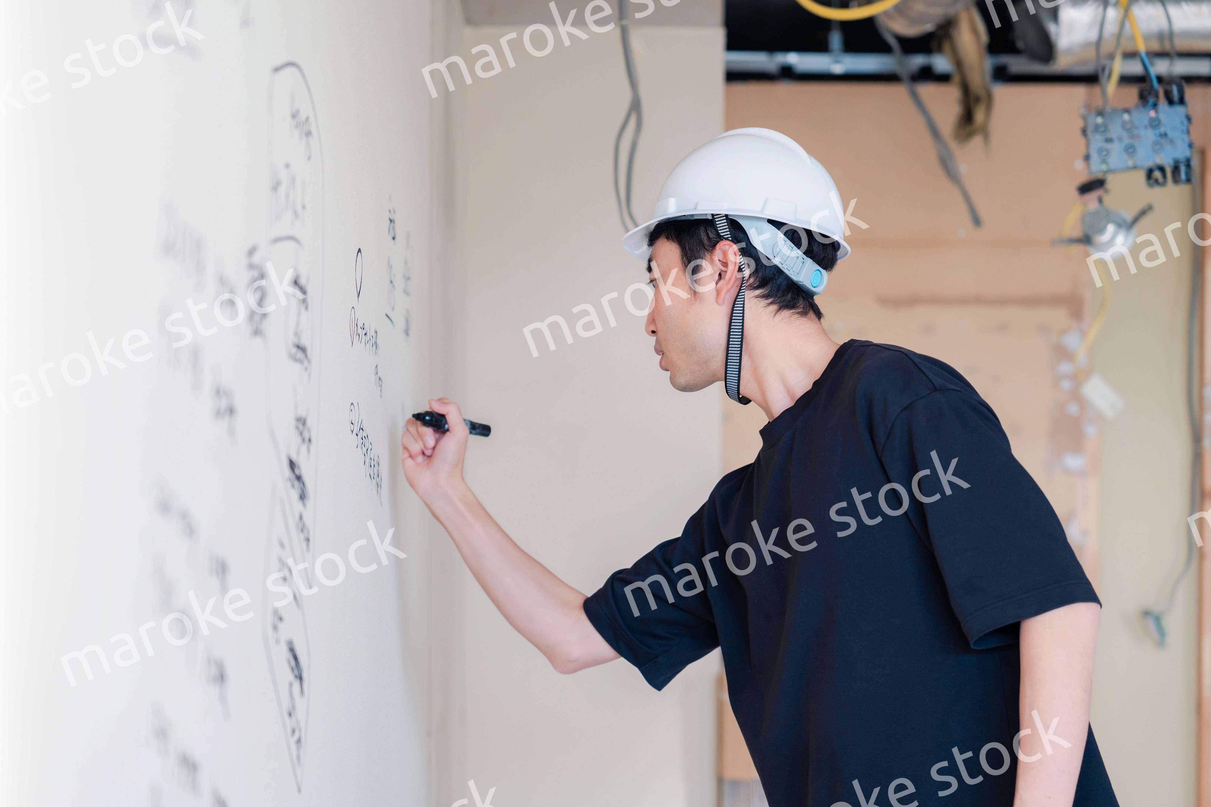 施工中の壁にメモを取る大工さん