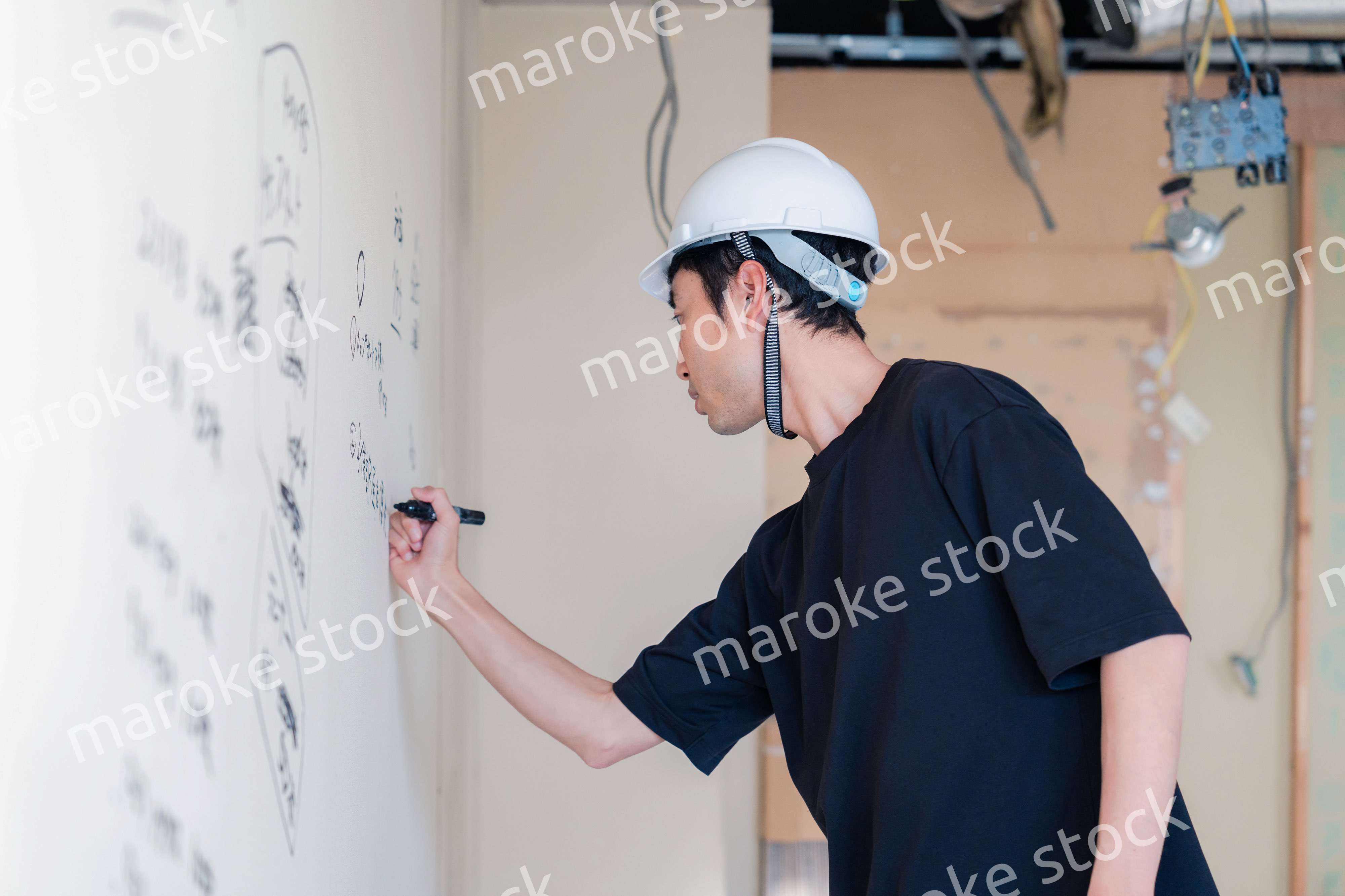 施工中の壁にメモを取る大工さん