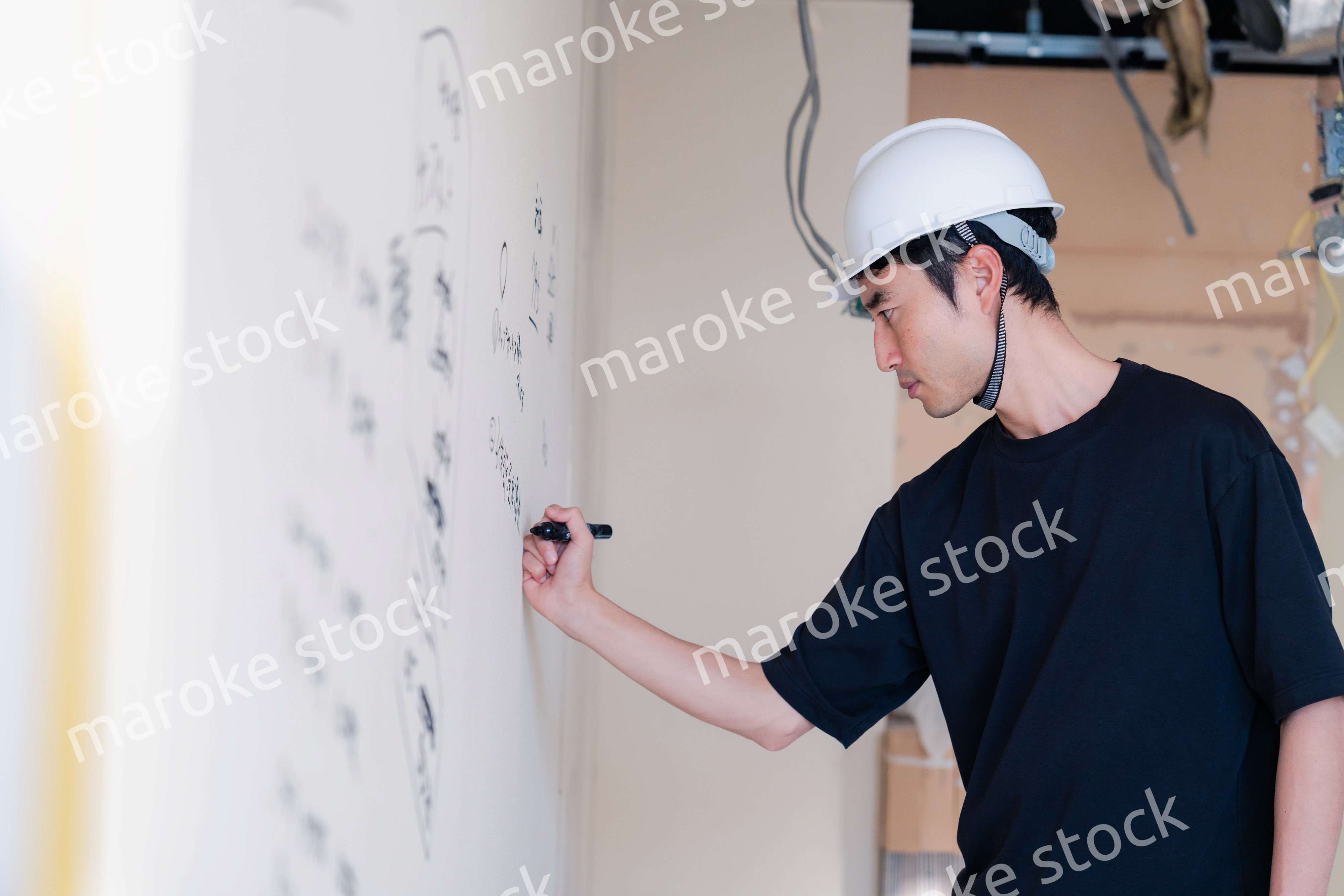 施工中の壁にメモを取る大工さん