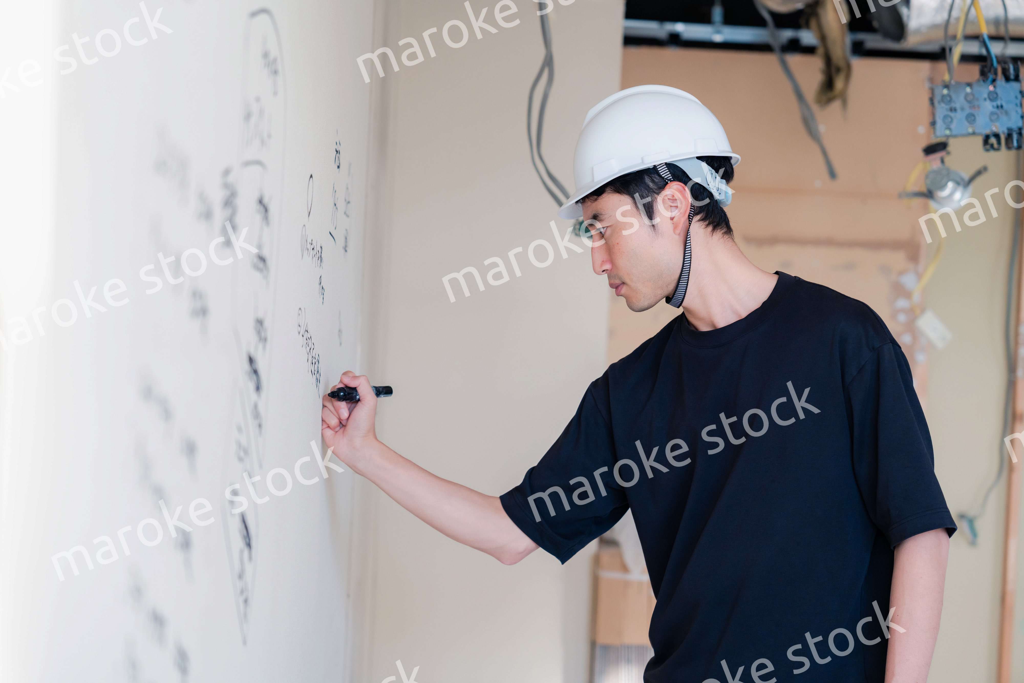 施工中の壁にメモを取る大工さん