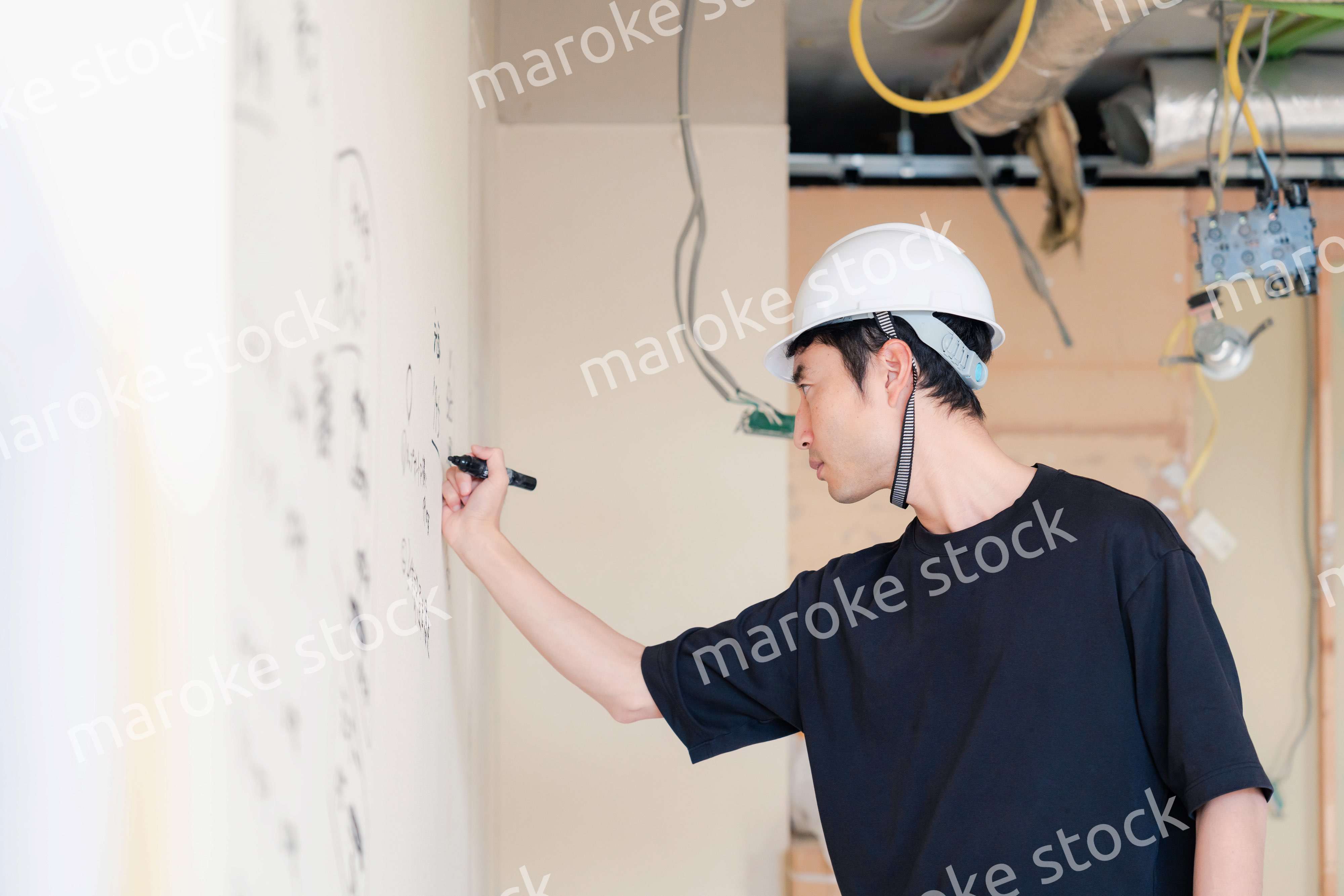 施工中の壁にメモを取る大工さん