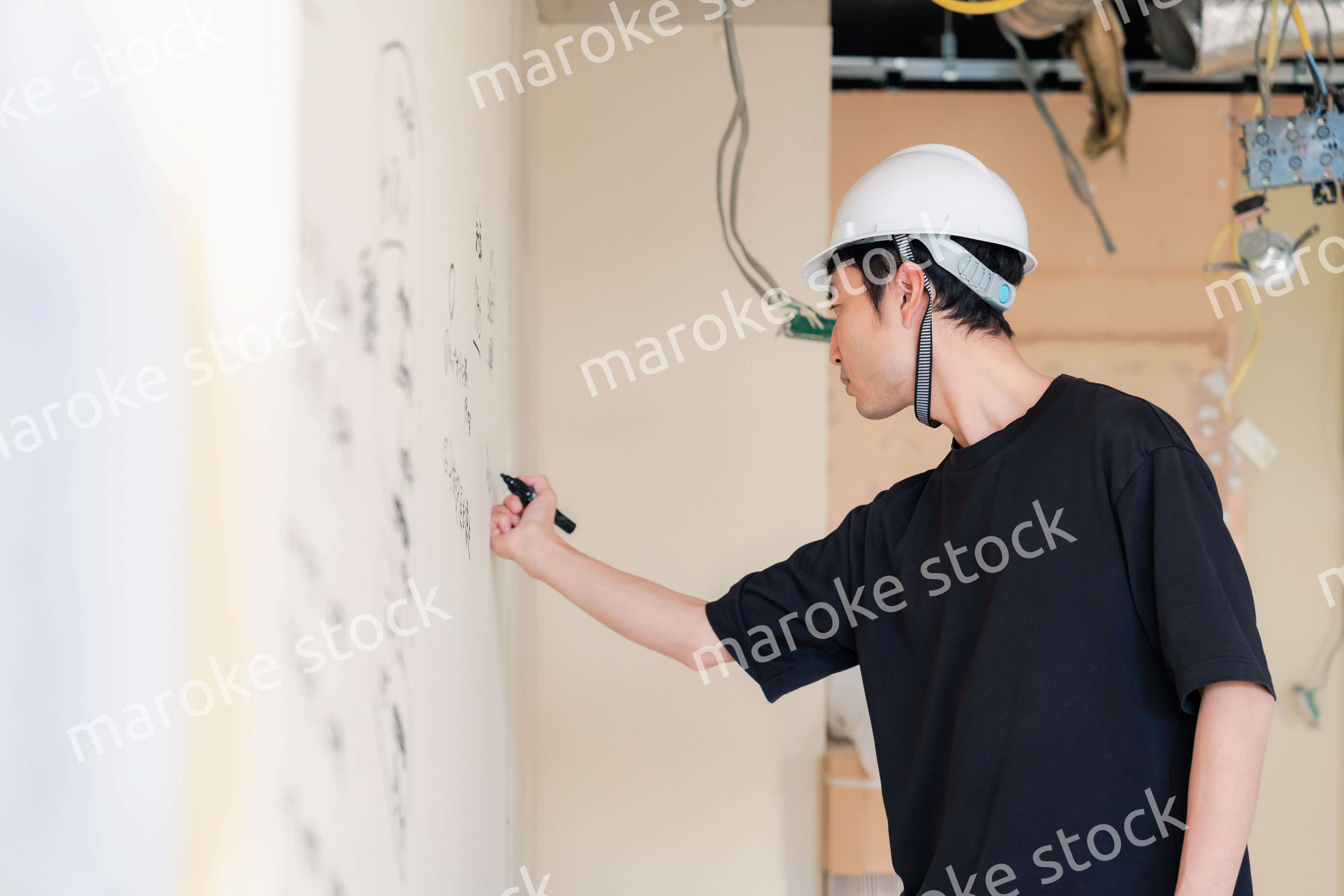 施工中の壁にメモを取る大工さん