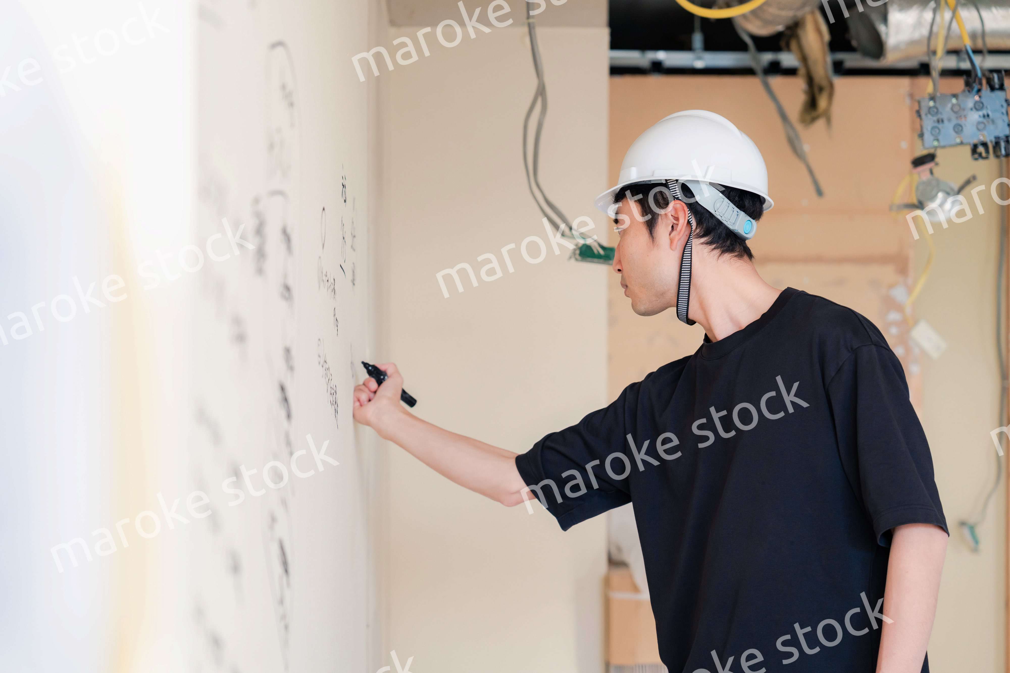 施工中の壁にメモを取る大工さん