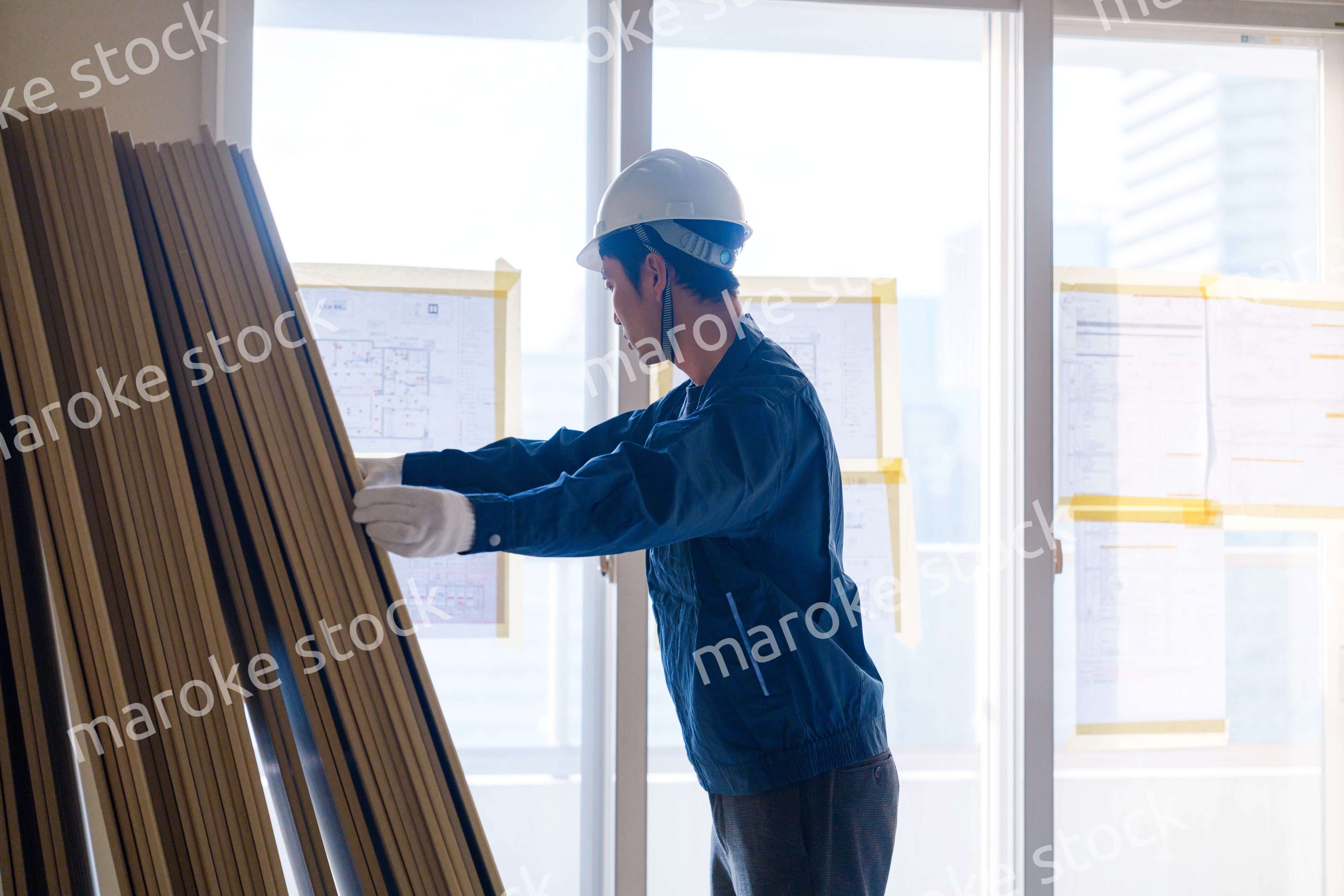 リフォーム工事の現場で石膏ボードを運ぶ職人