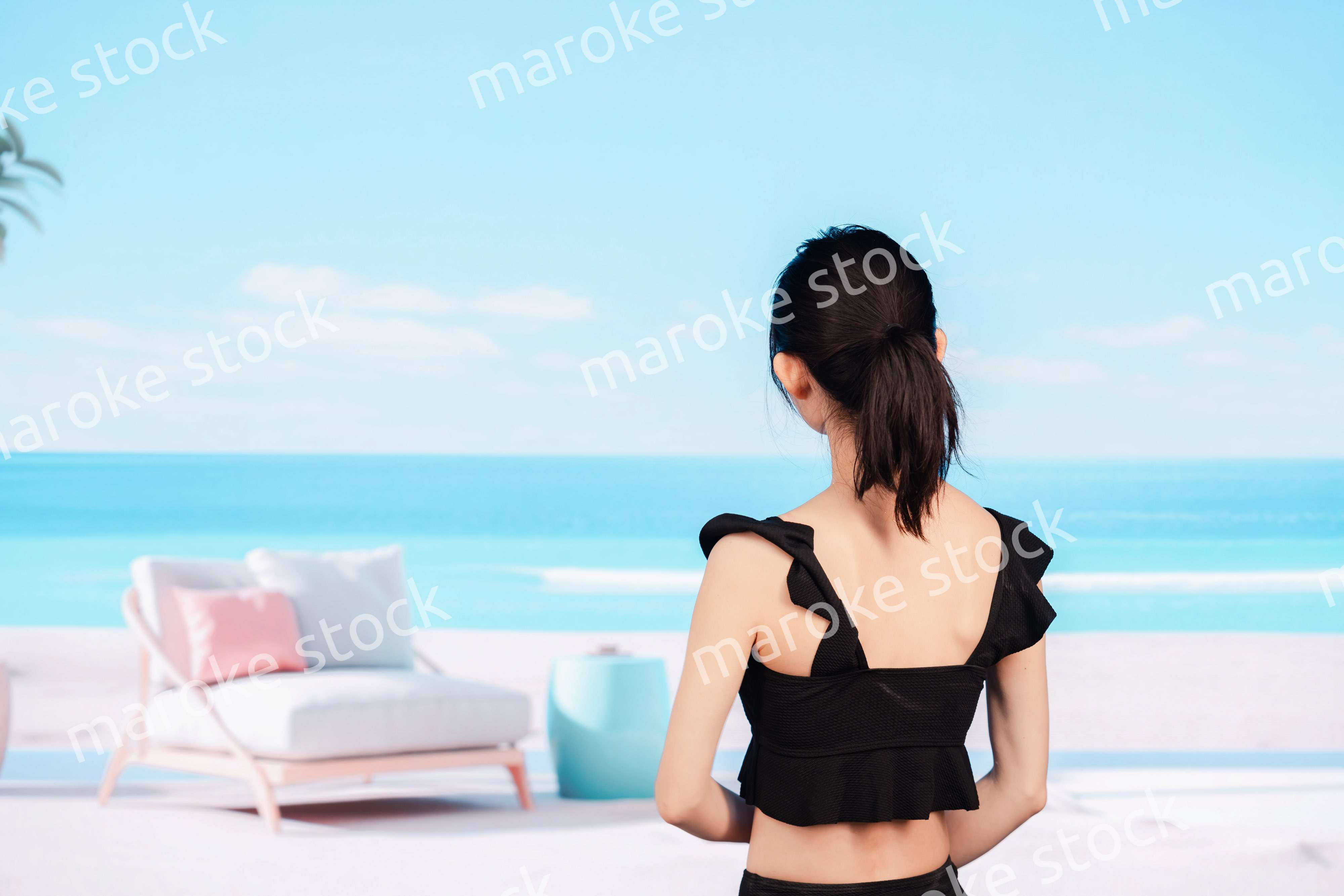 水着を着て海を眺める若い女性