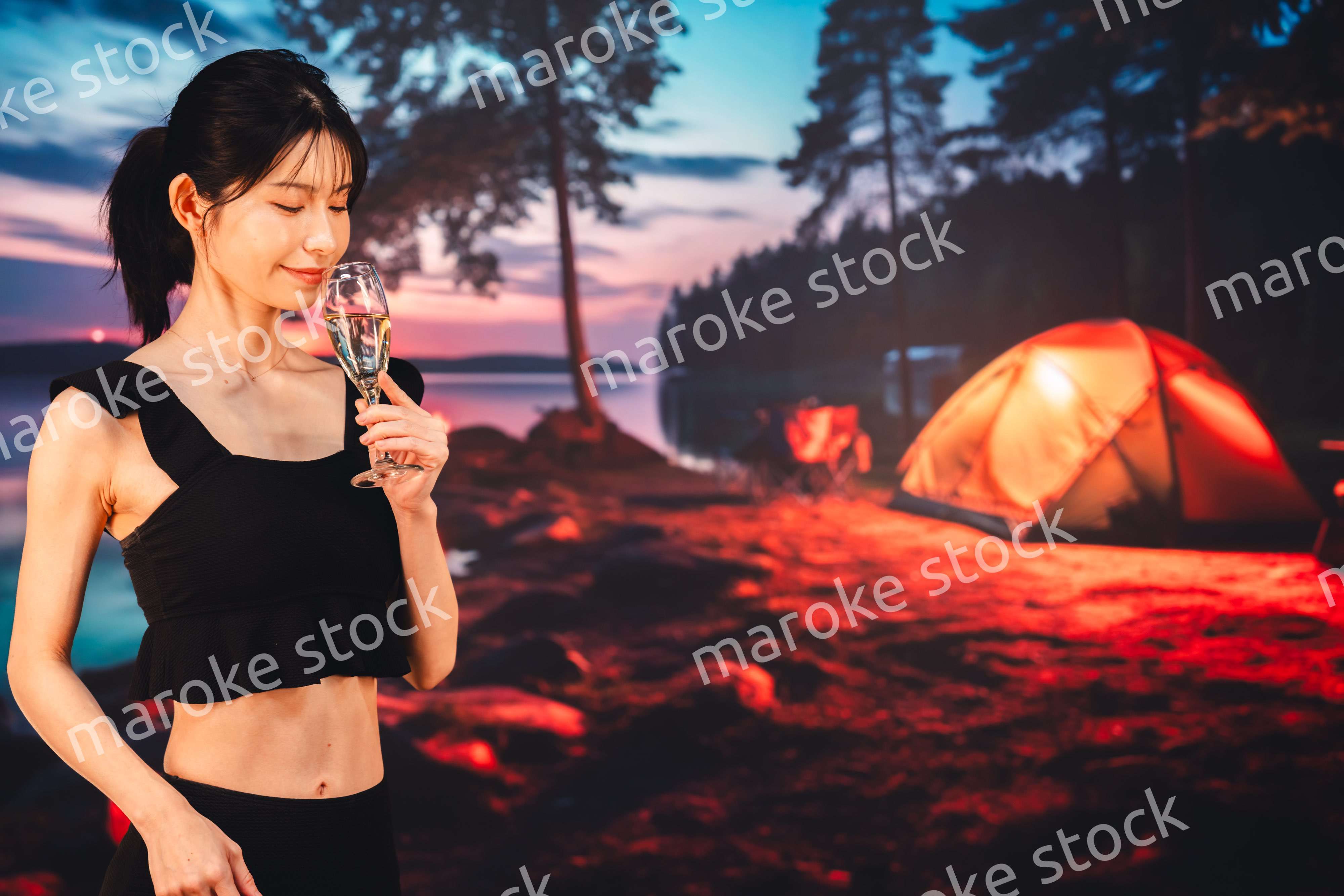 キャンプをしながらスパークリングワインを飲む女性