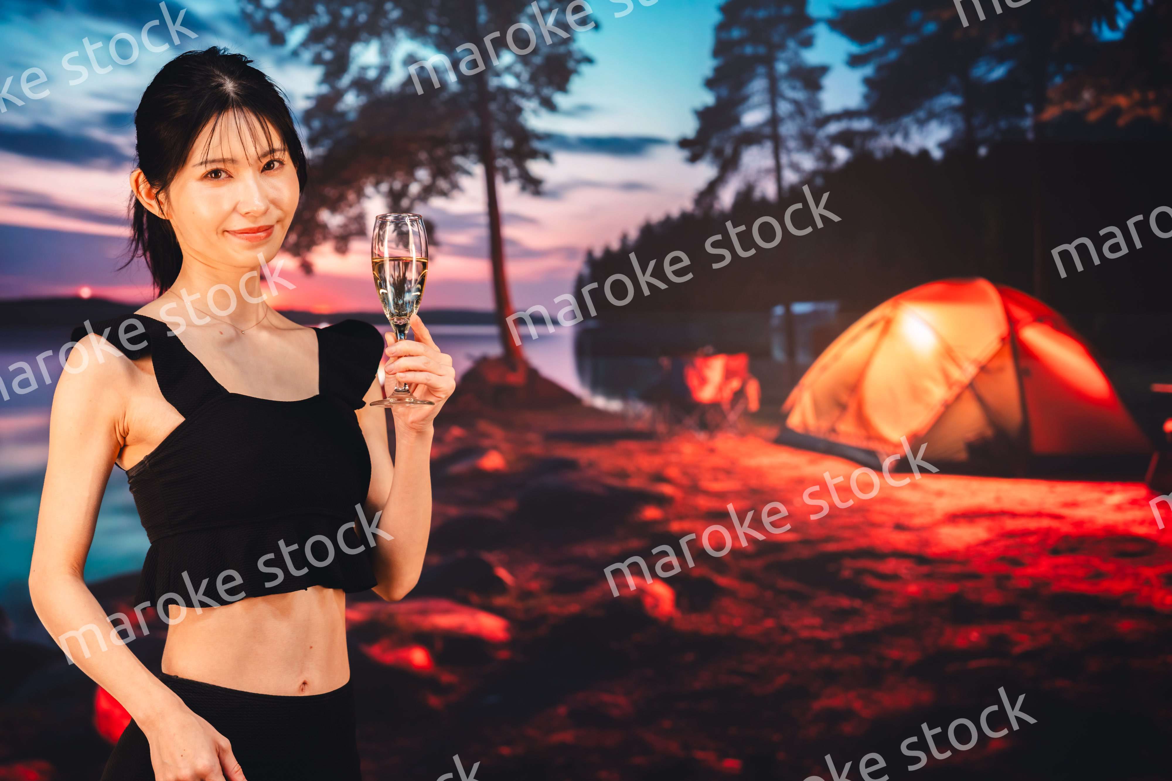 キャンプをしながらスパークリングワインを飲む女性