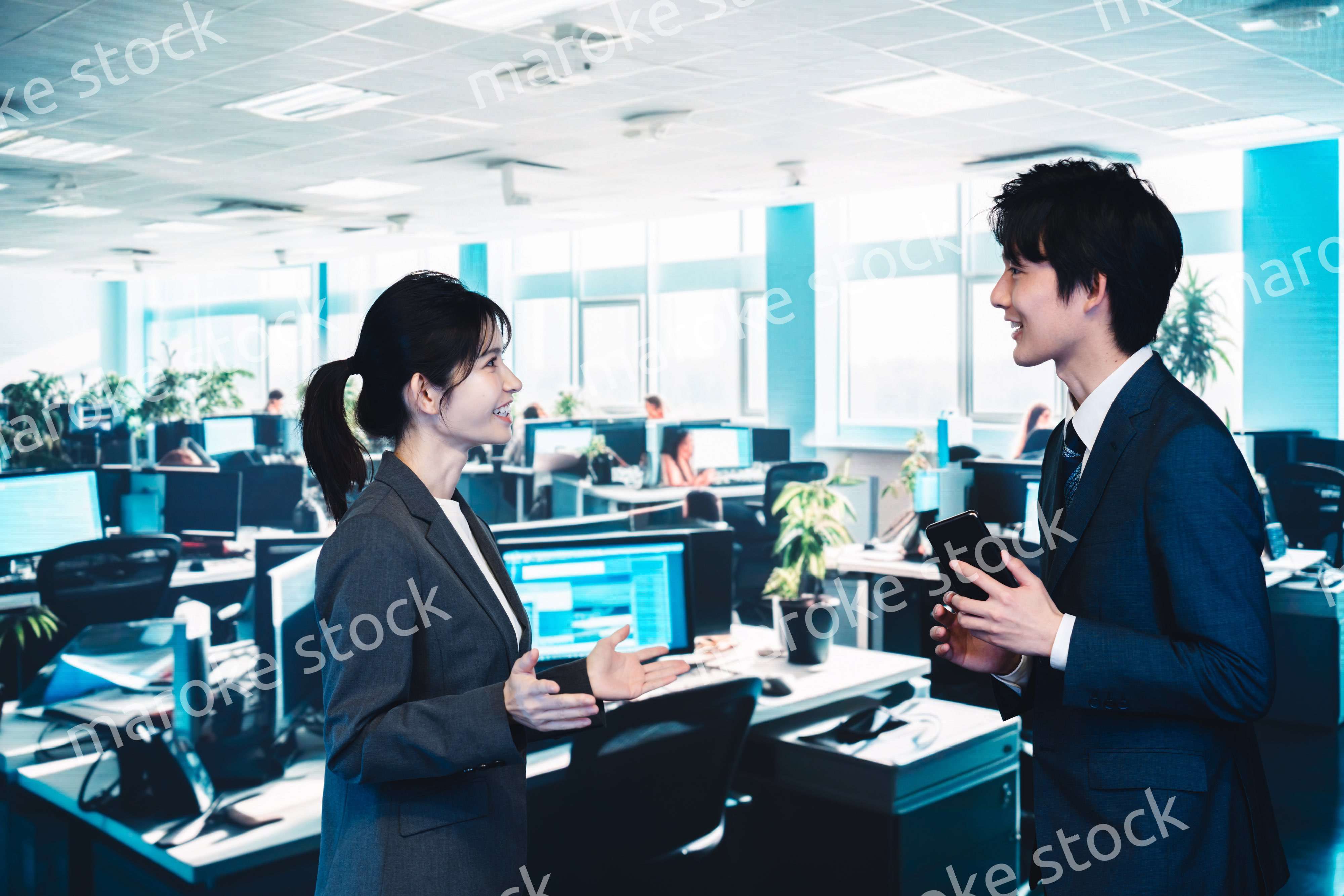 オフィスで楽しく話す男女のビジネスパーソン