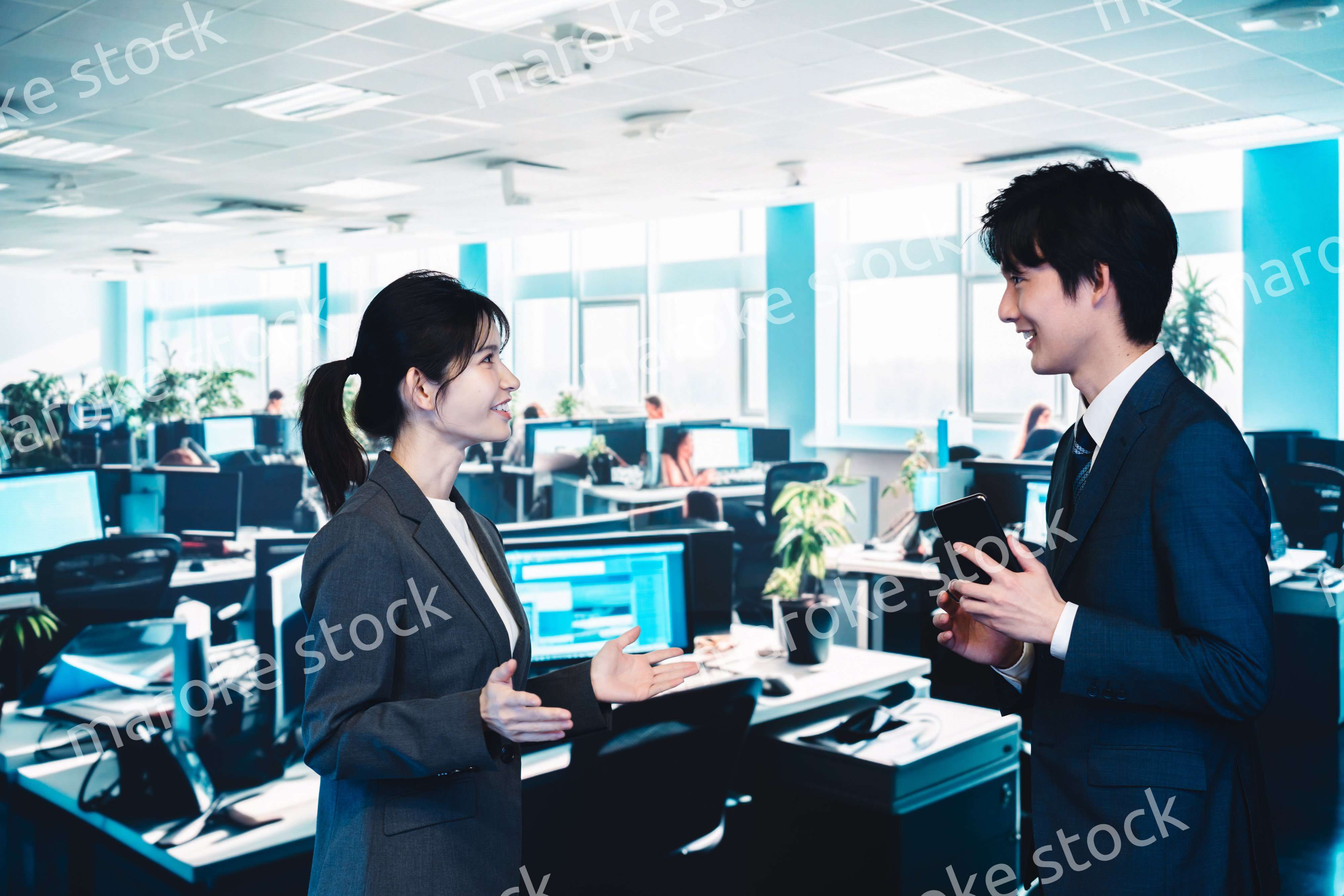 オフィスで楽しく話す男女のビジネスパーソン