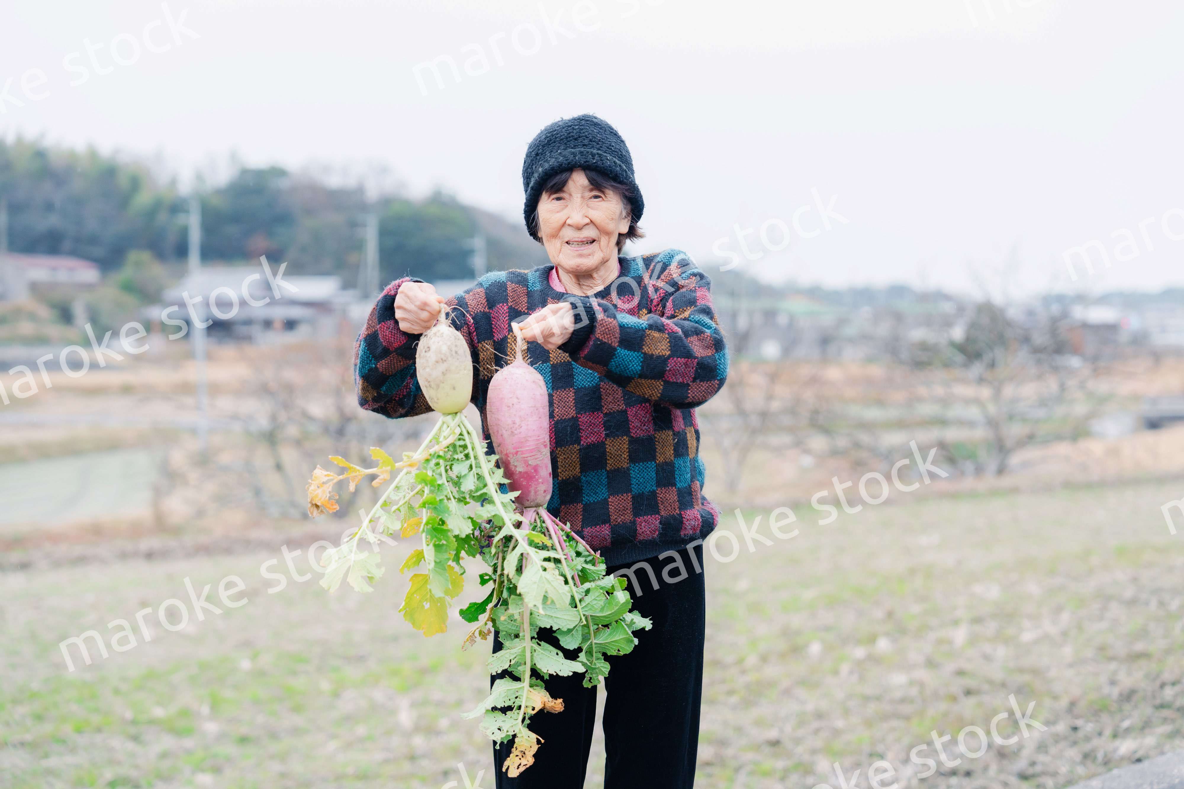 畑で野菜を持つ高齢の女性