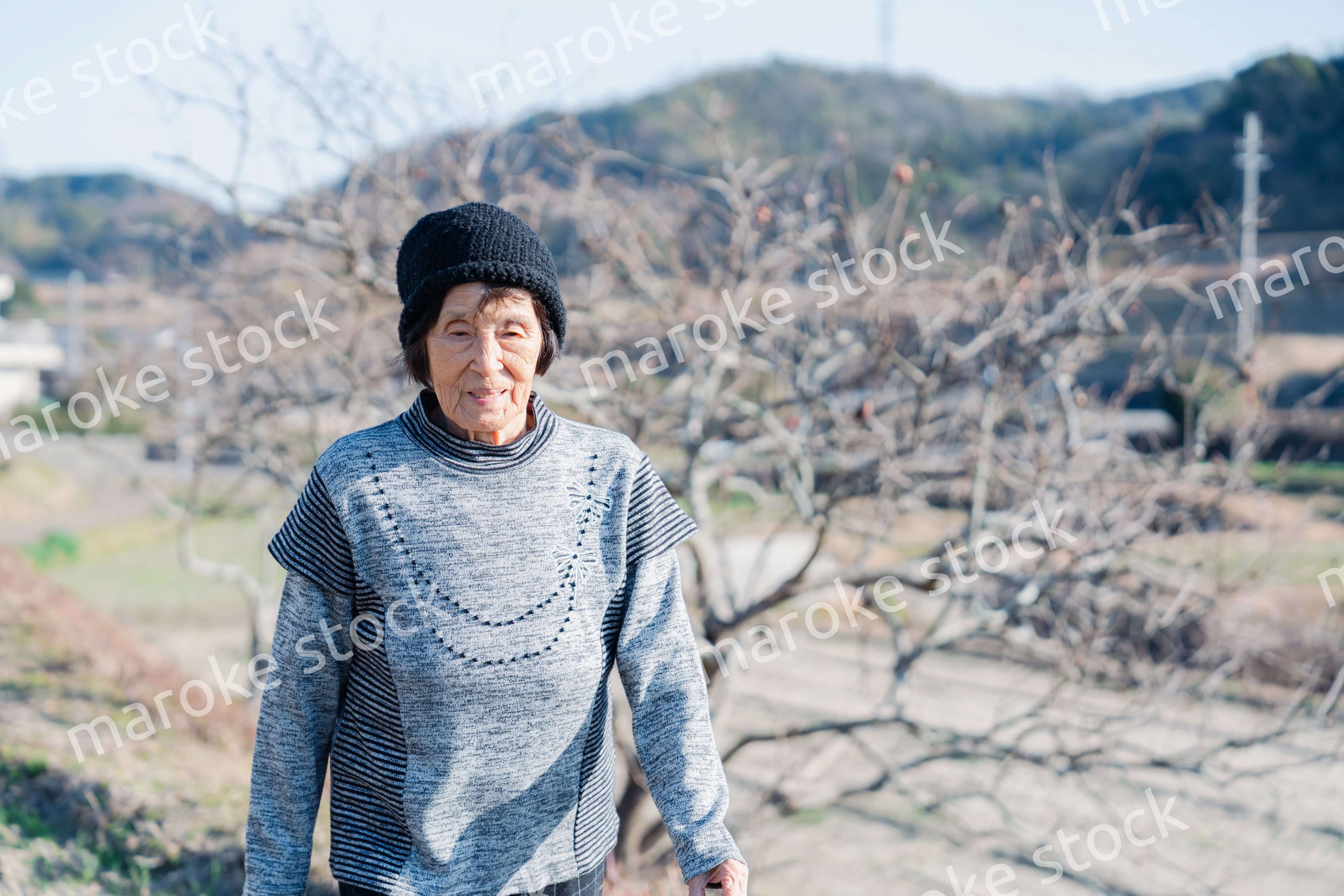 田舎の道を散歩する高齢の女性