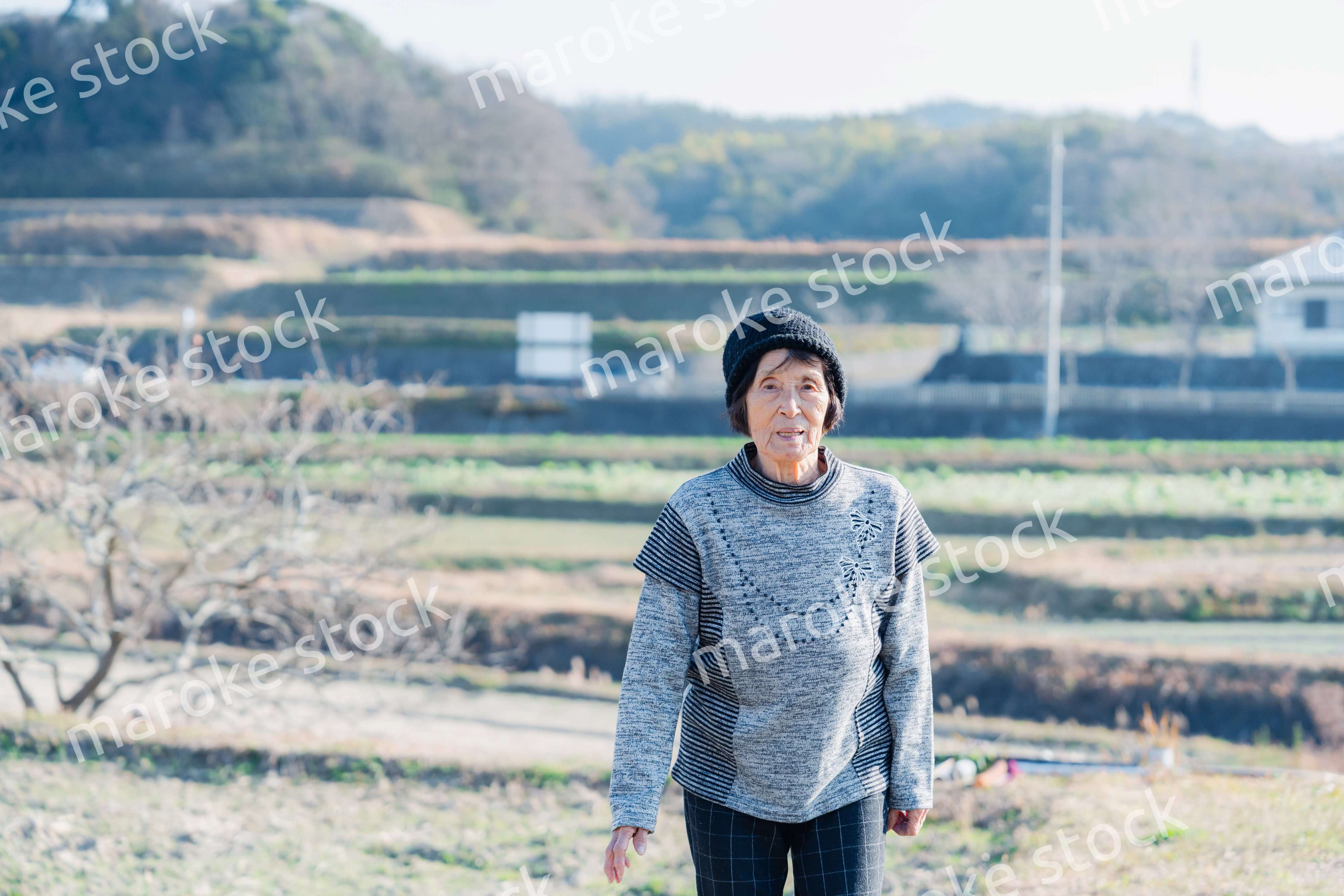 田舎の道を散歩する高齢の女性