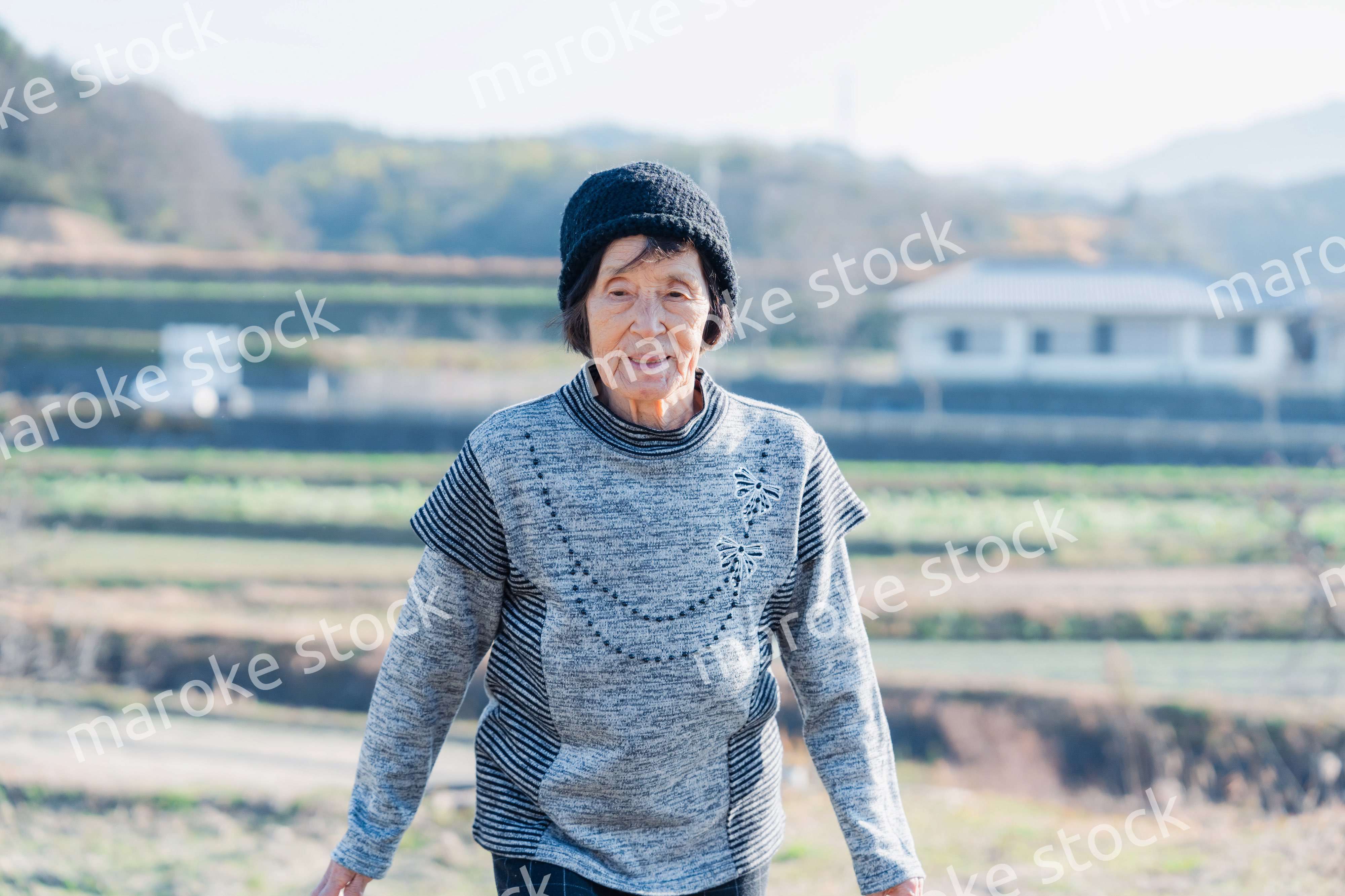 田舎の道を散歩する高齢の女性