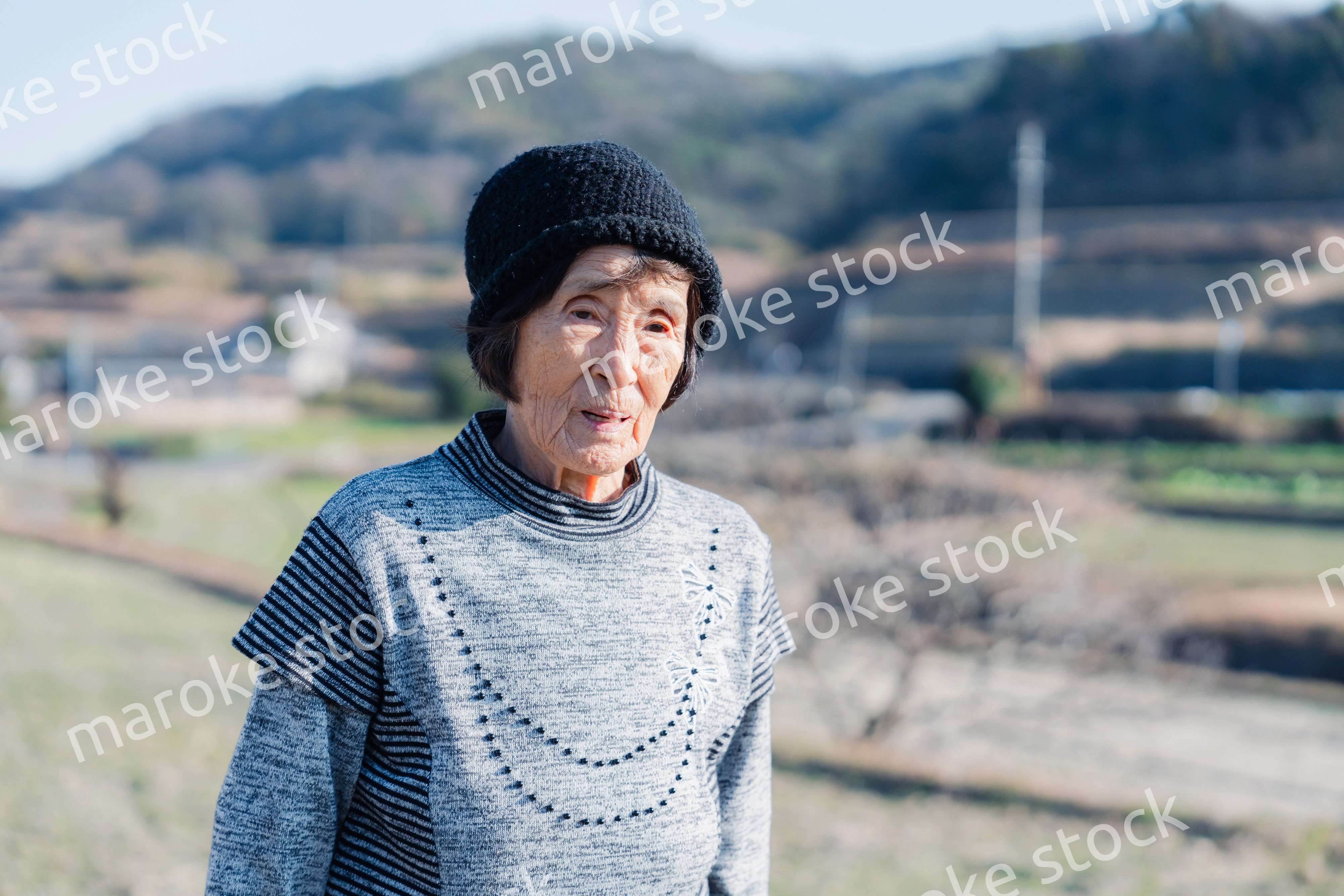 田舎の道を散歩する高齢の女性