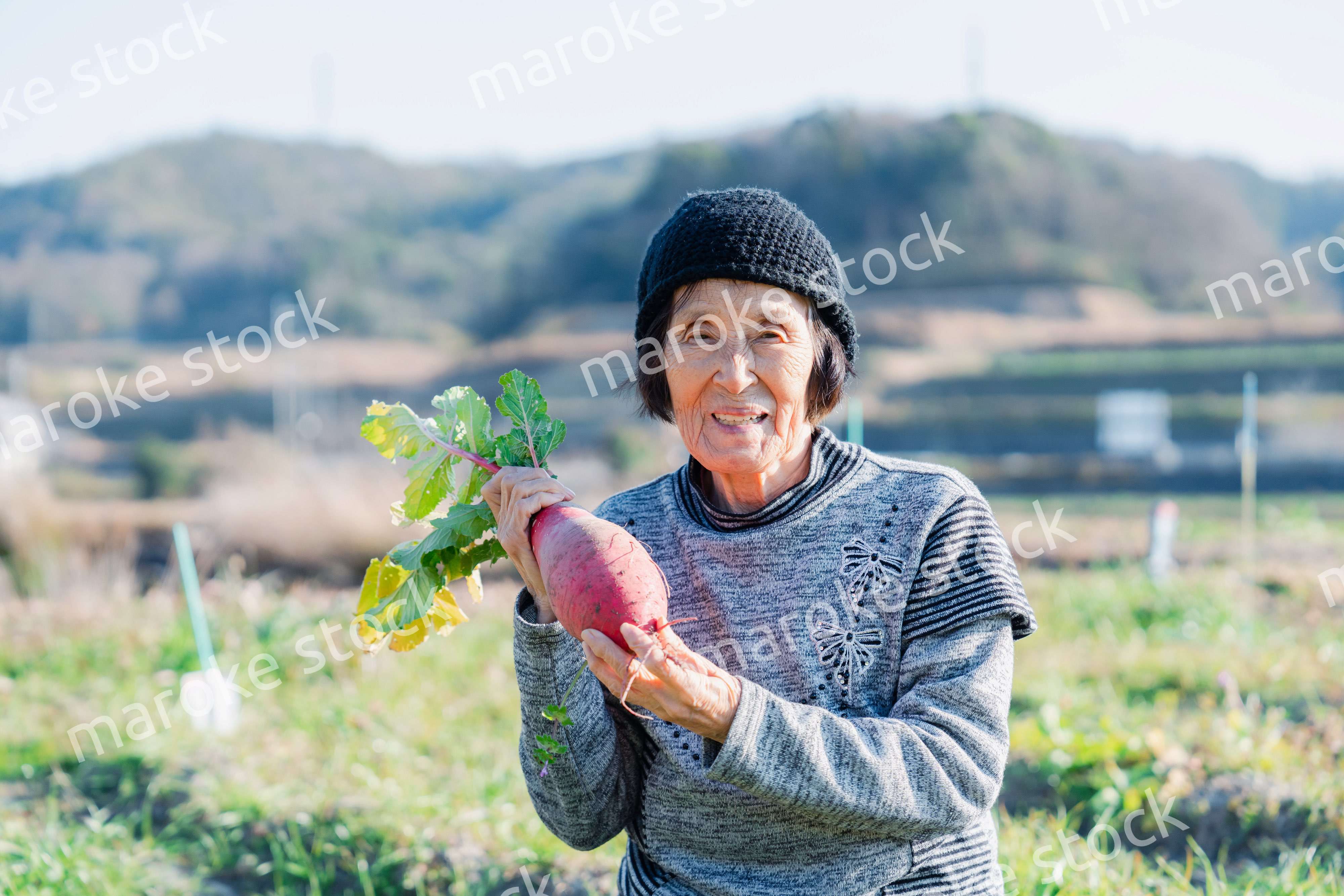 畑で野菜を持つ高齢の女性