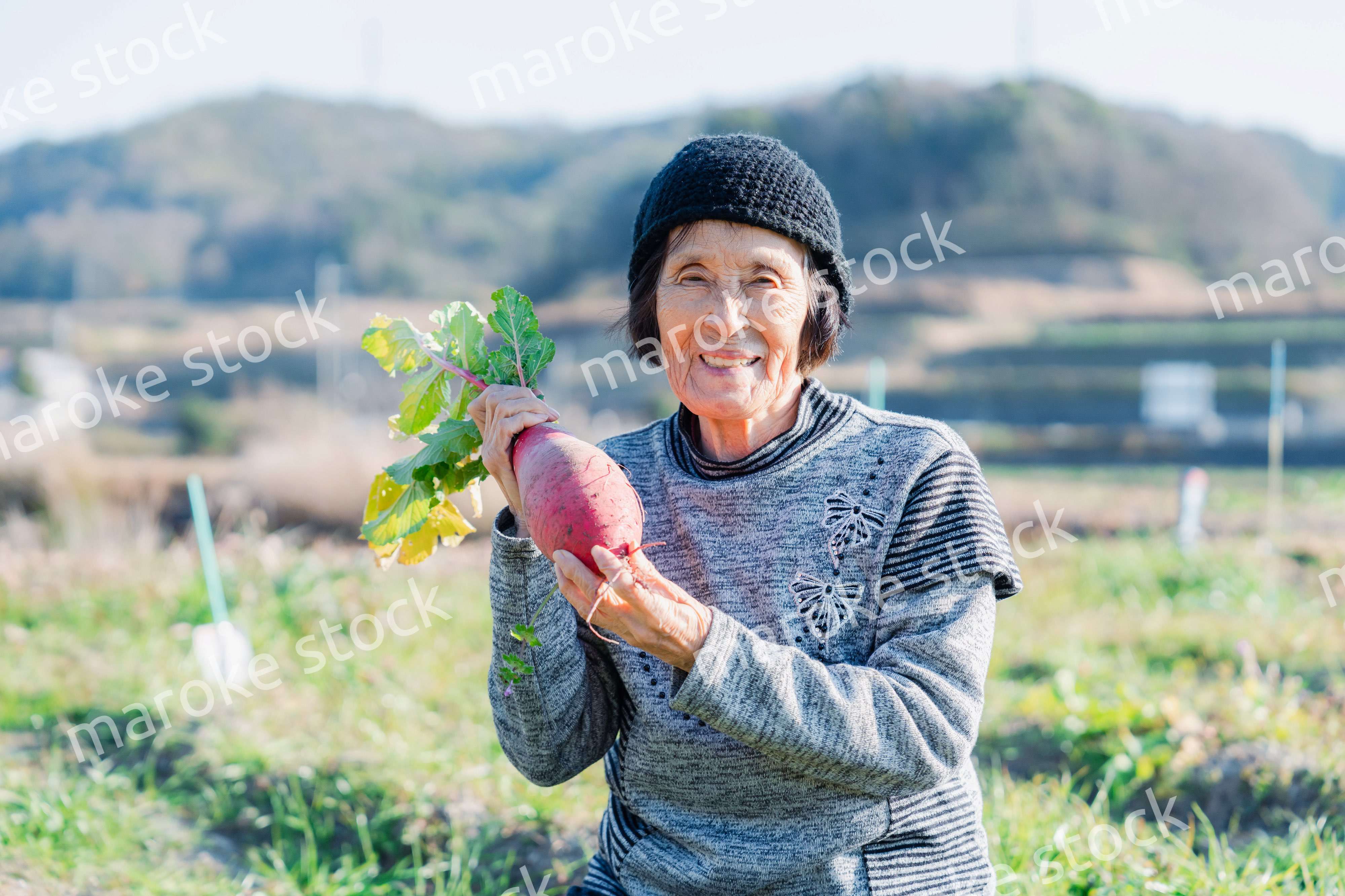 畑で野菜を持つ高齢の女性