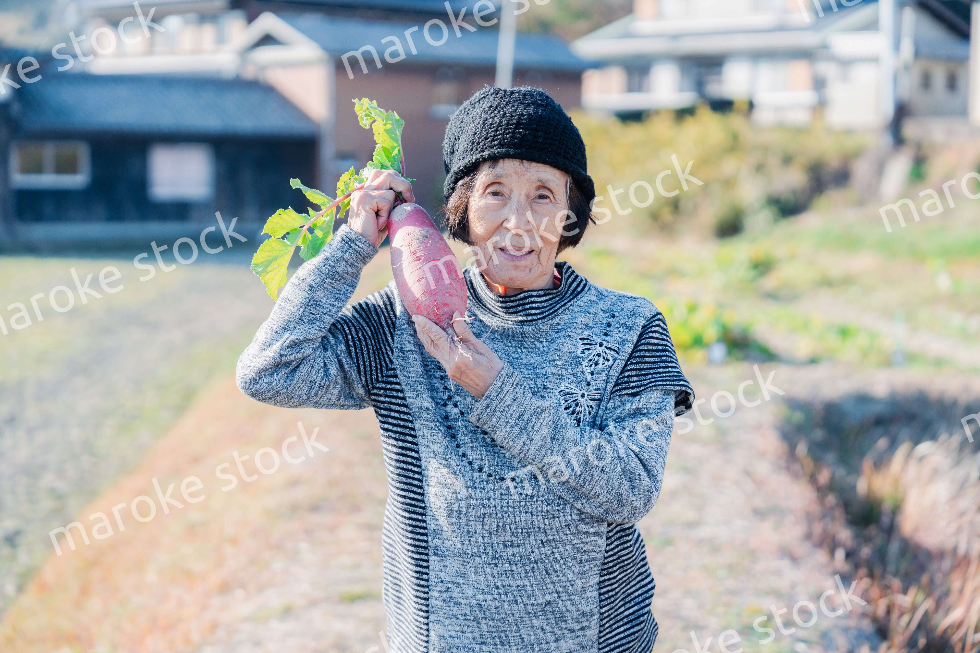 畑で野菜を持つ高齢の女性