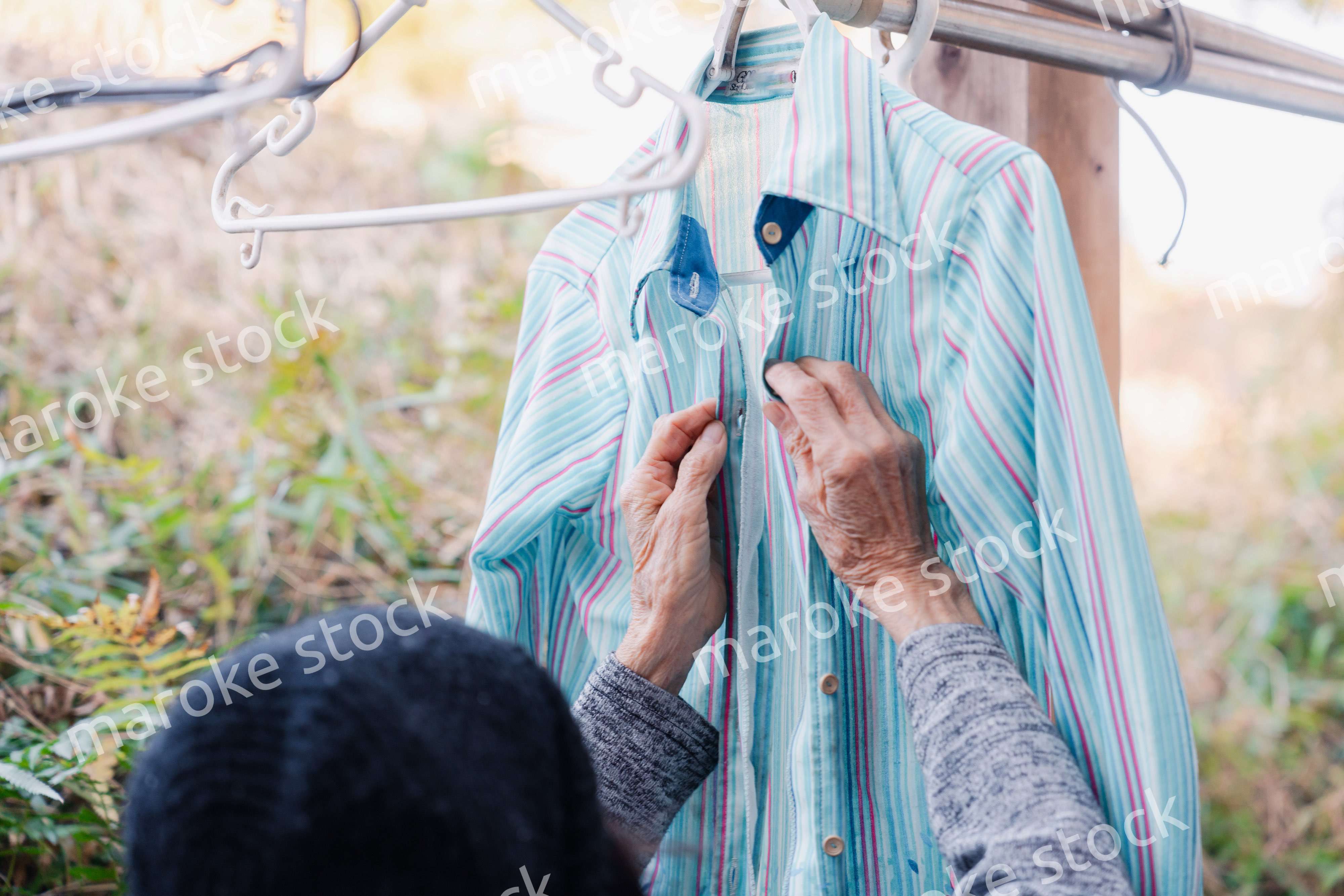 外に洗濯物を干す高齢の女性