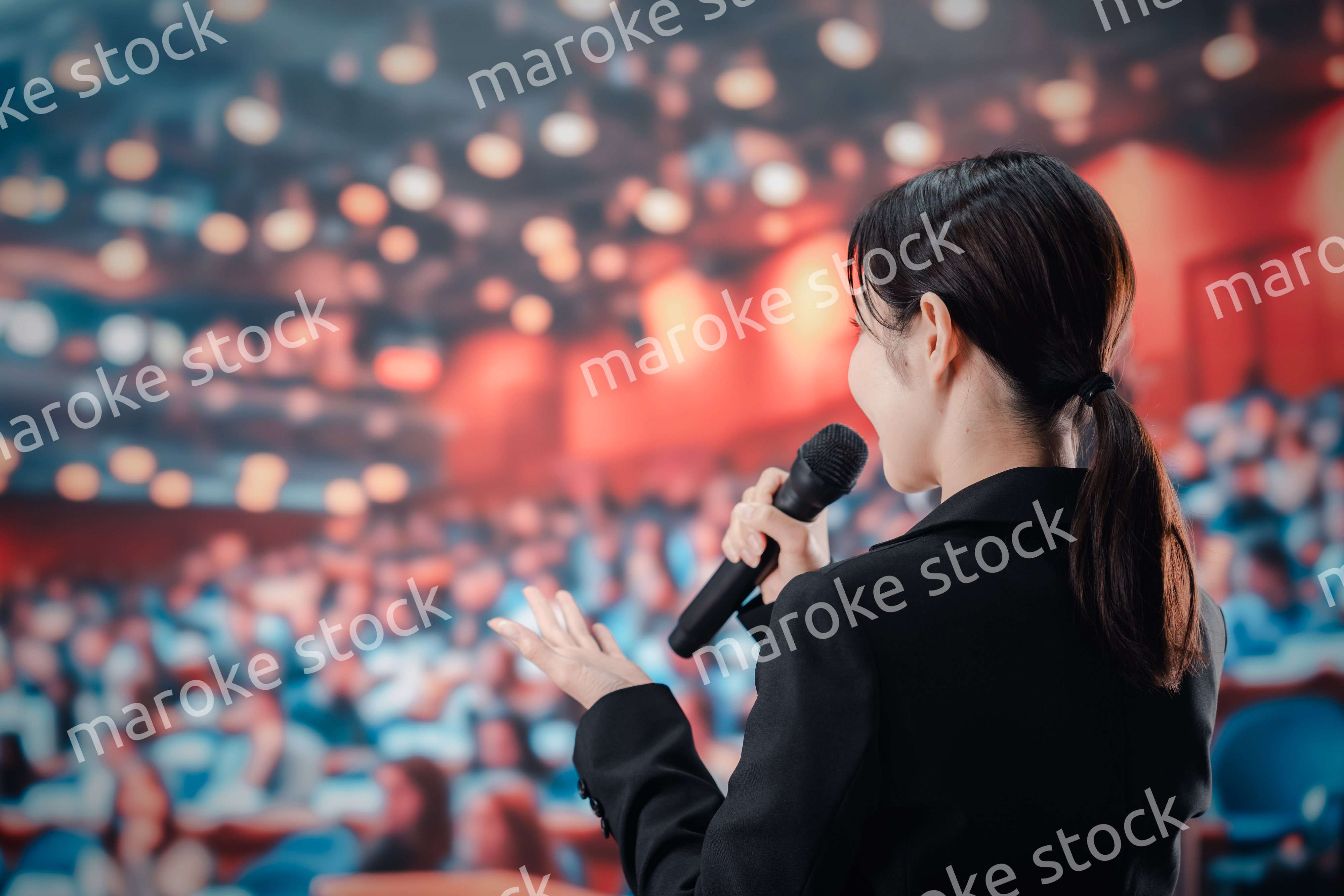 大勢の聴衆の前でスピーチをする女性