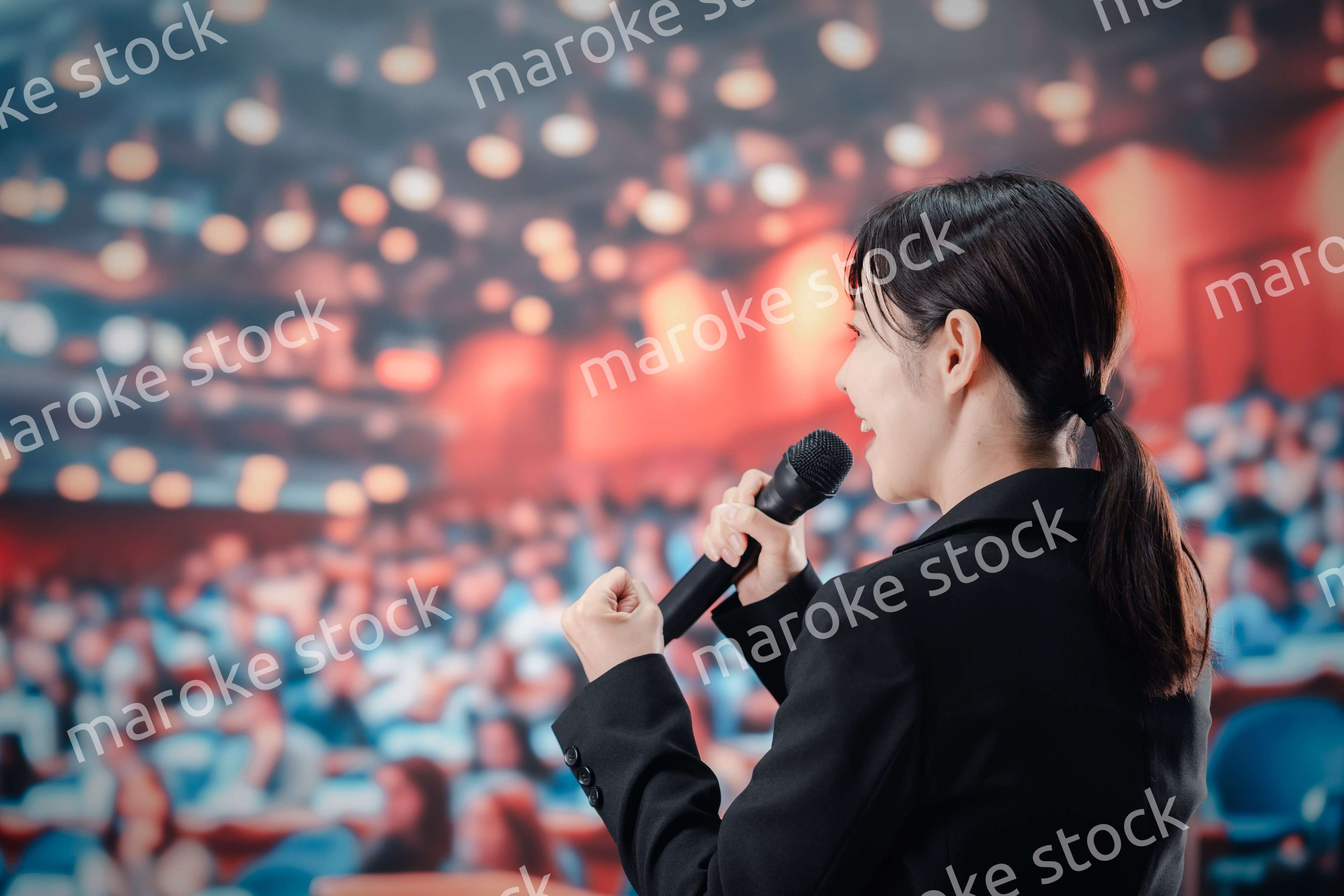 大勢の聴衆の前でスピーチをする女性