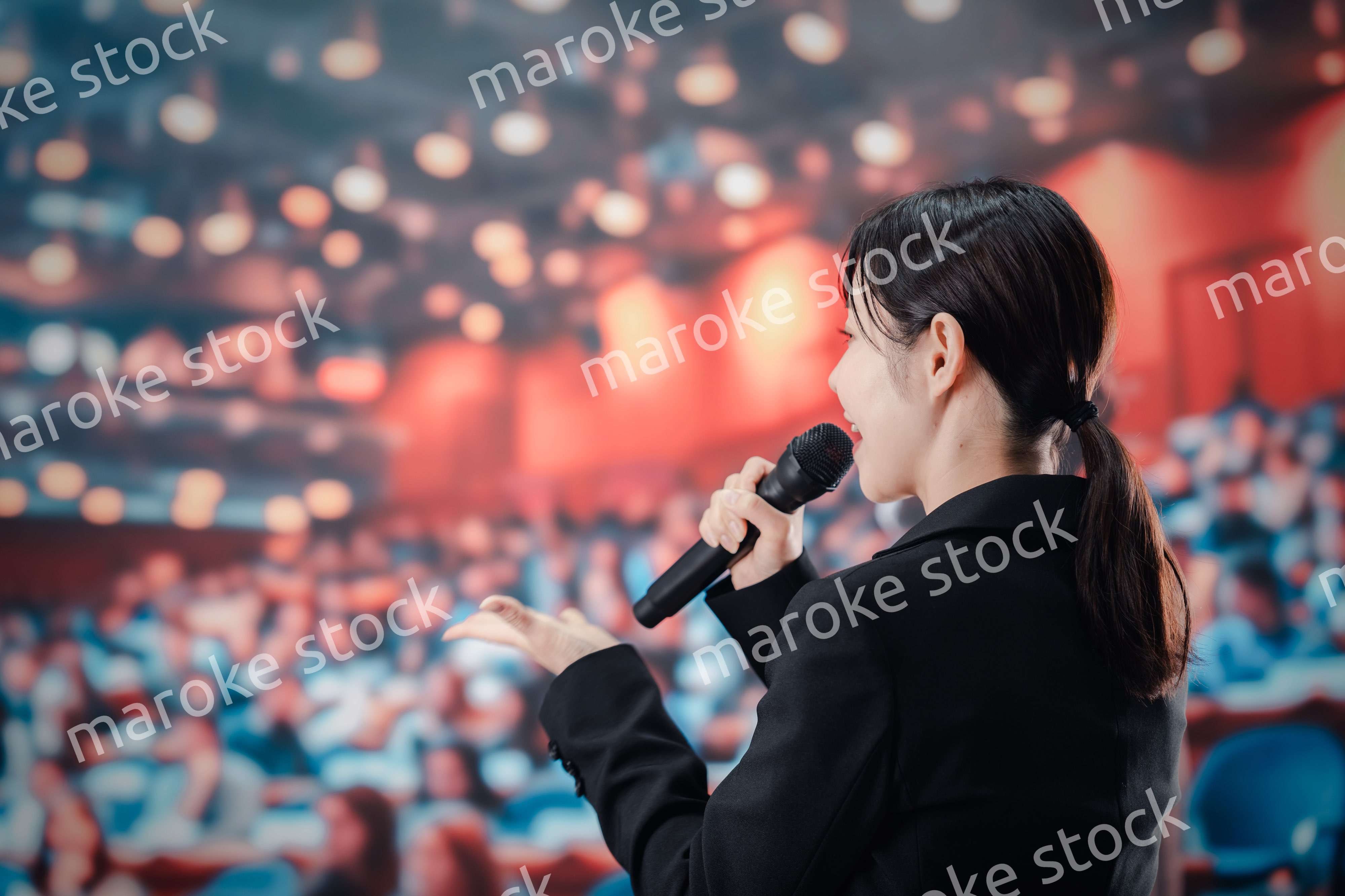 大勢の聴衆の前でスピーチをする女性