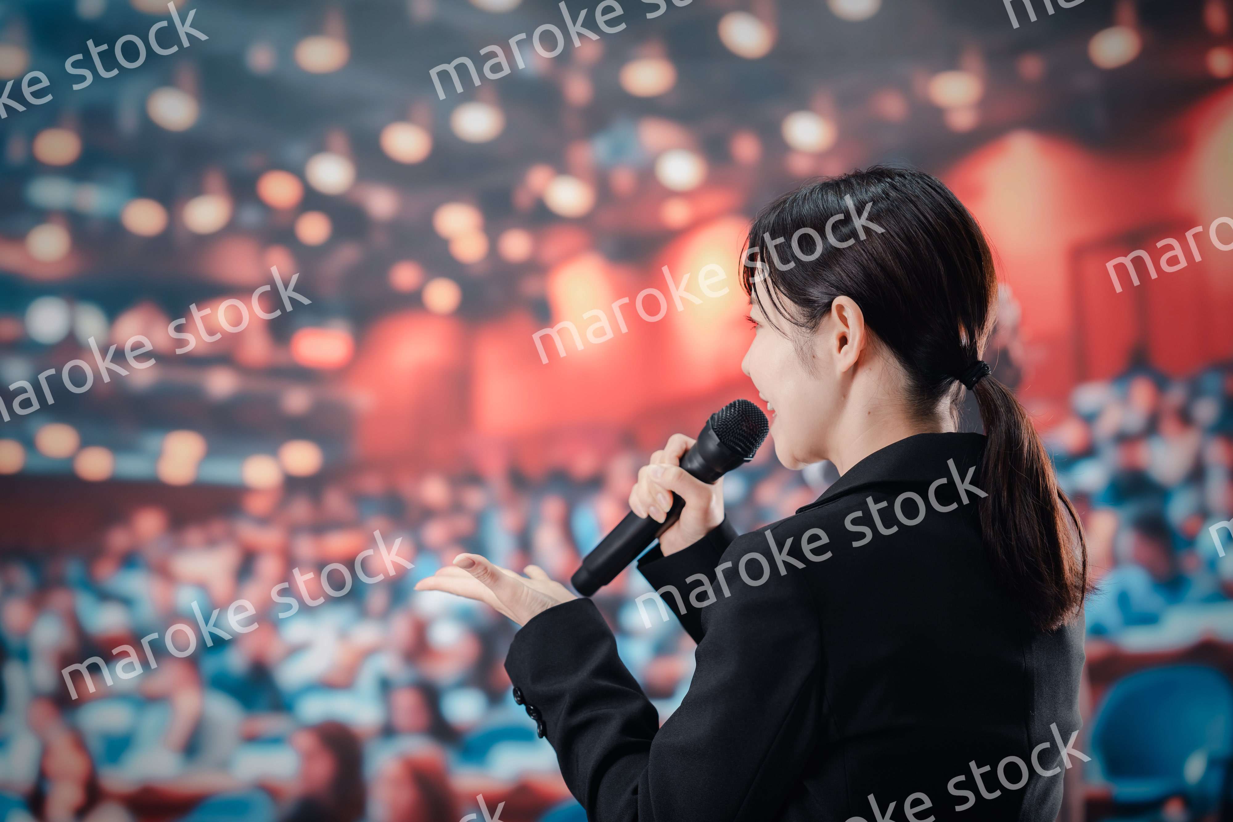 大勢の聴衆の前でスピーチをする女性