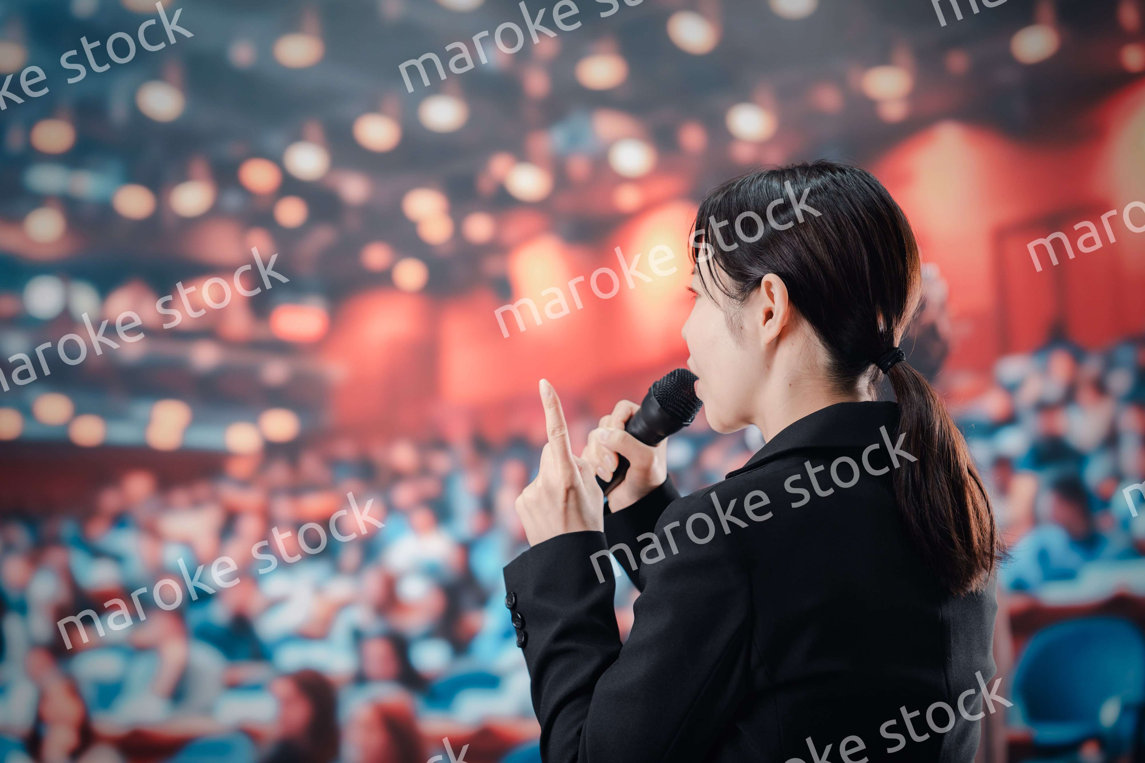 大勢の聴衆の前でスピーチをする女性