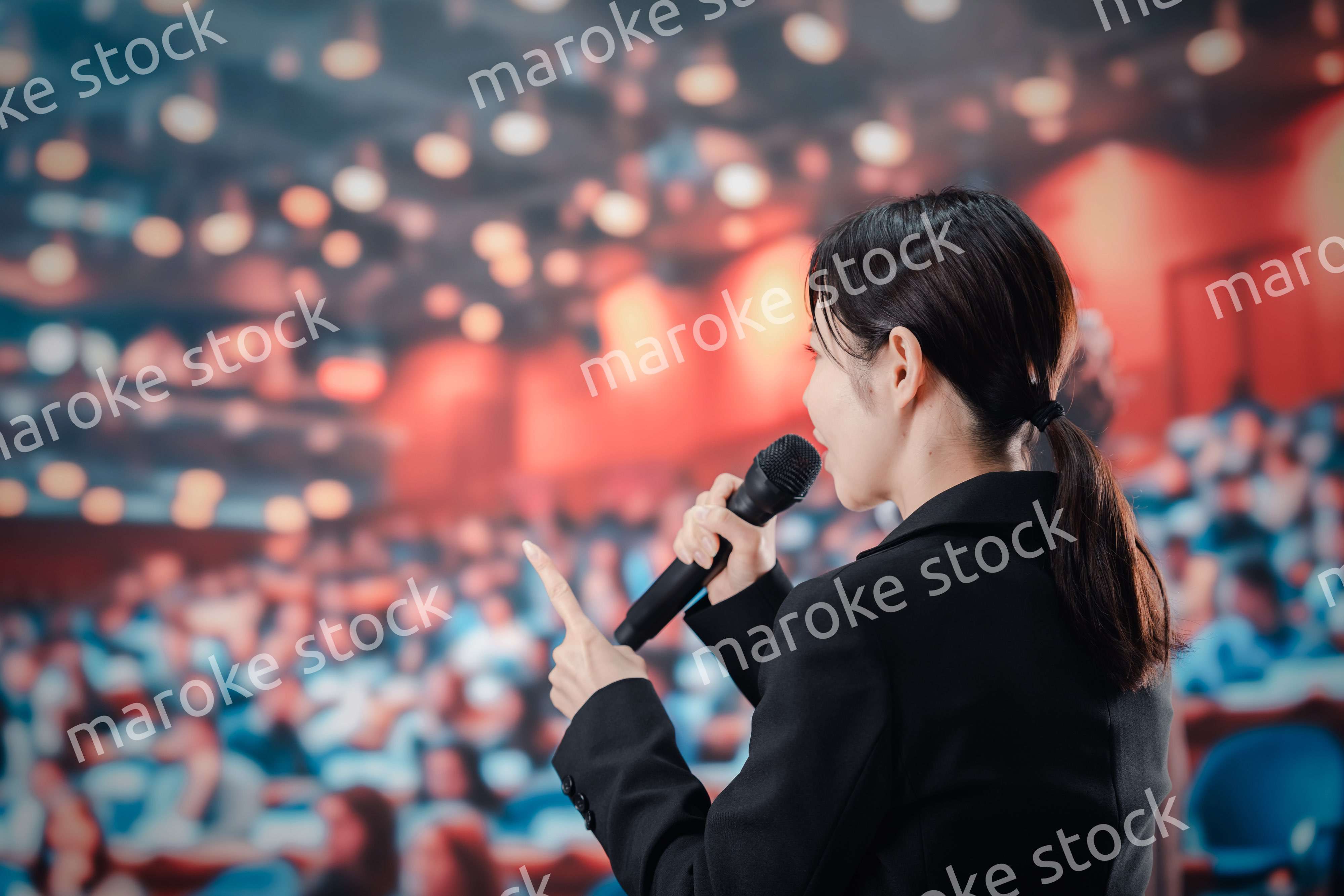 大勢の聴衆の前でスピーチをする女性