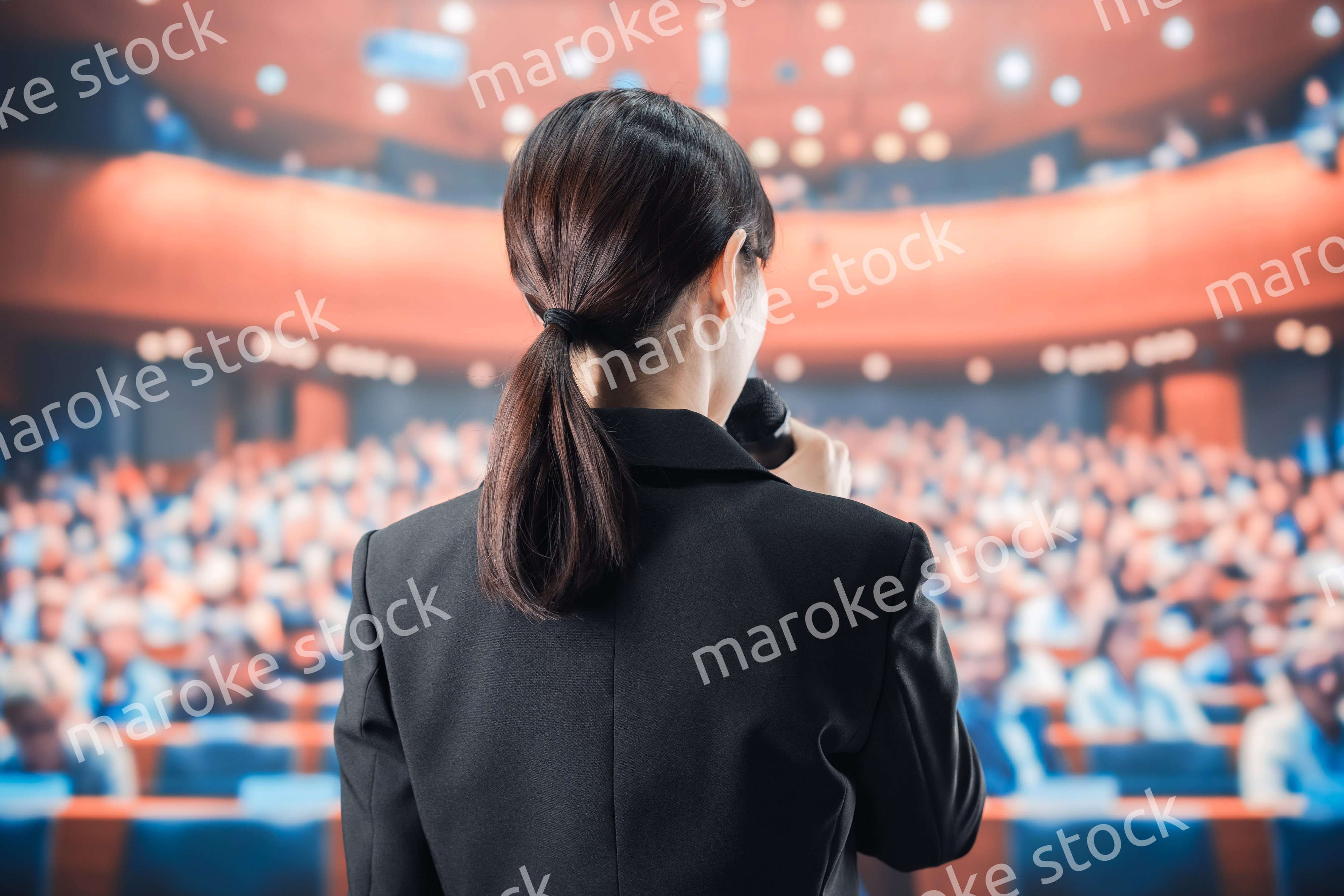 大勢の前でマイクで話す女性