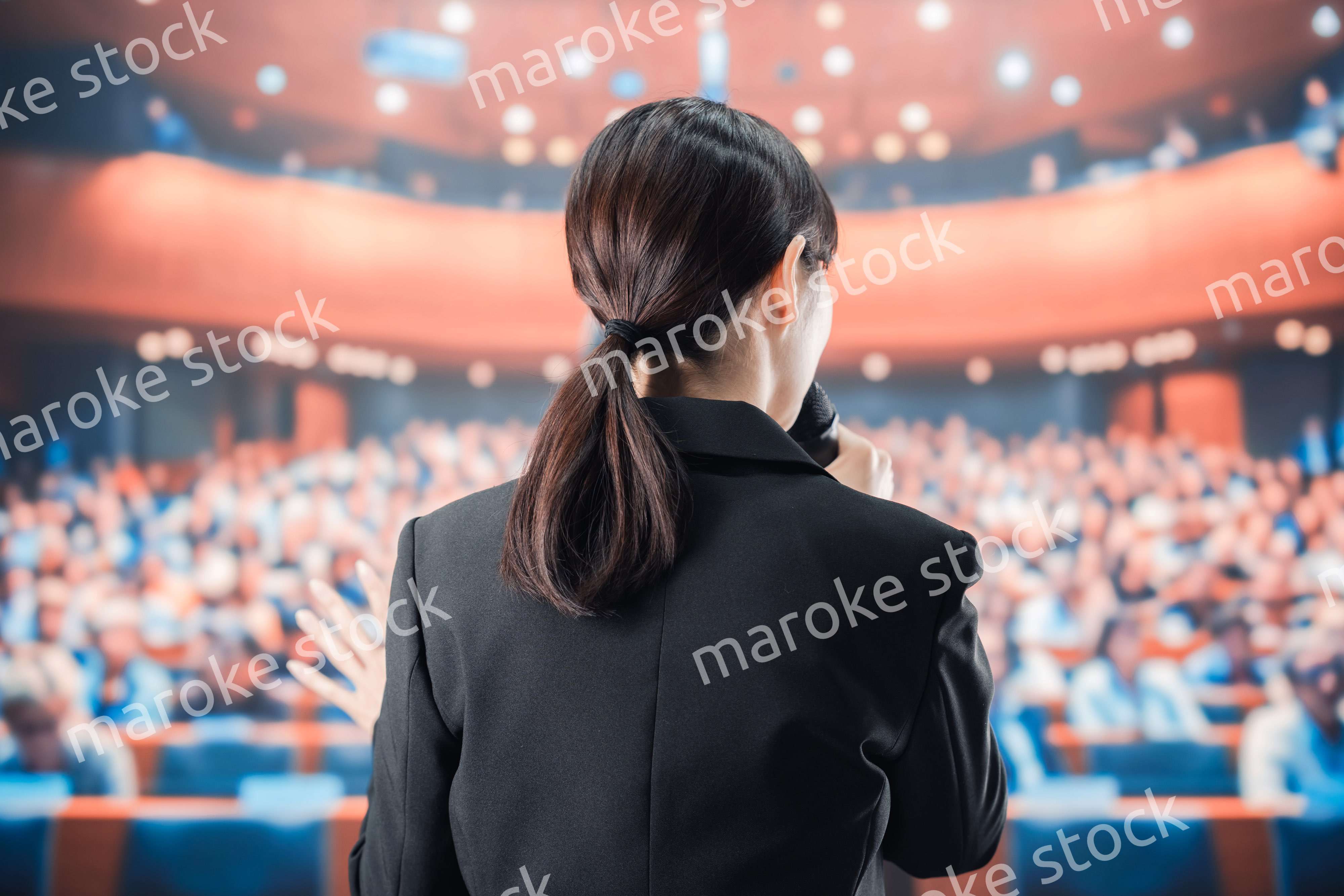 大勢の前でマイクで話す女性