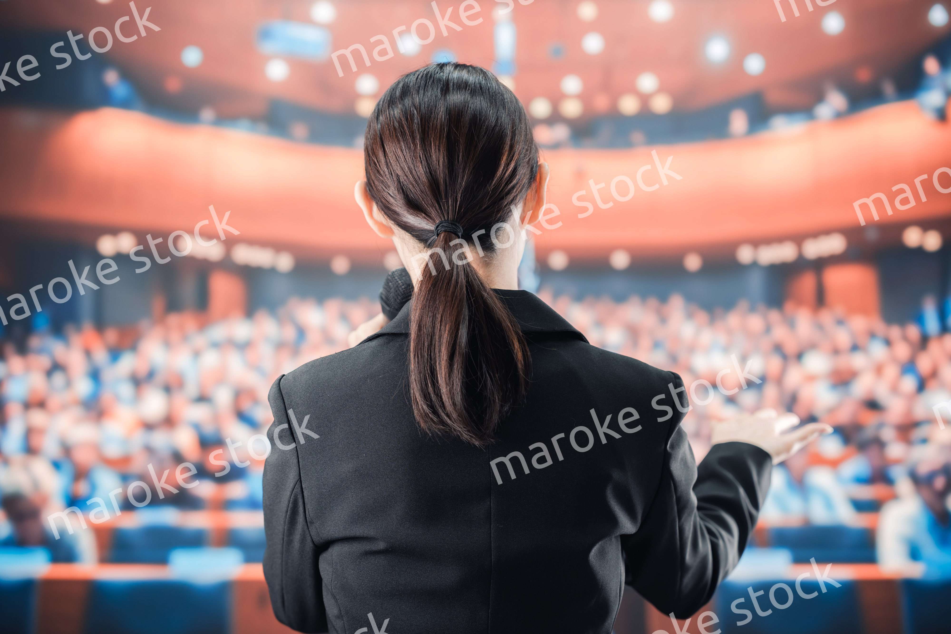 大勢の前でマイクで話す女性