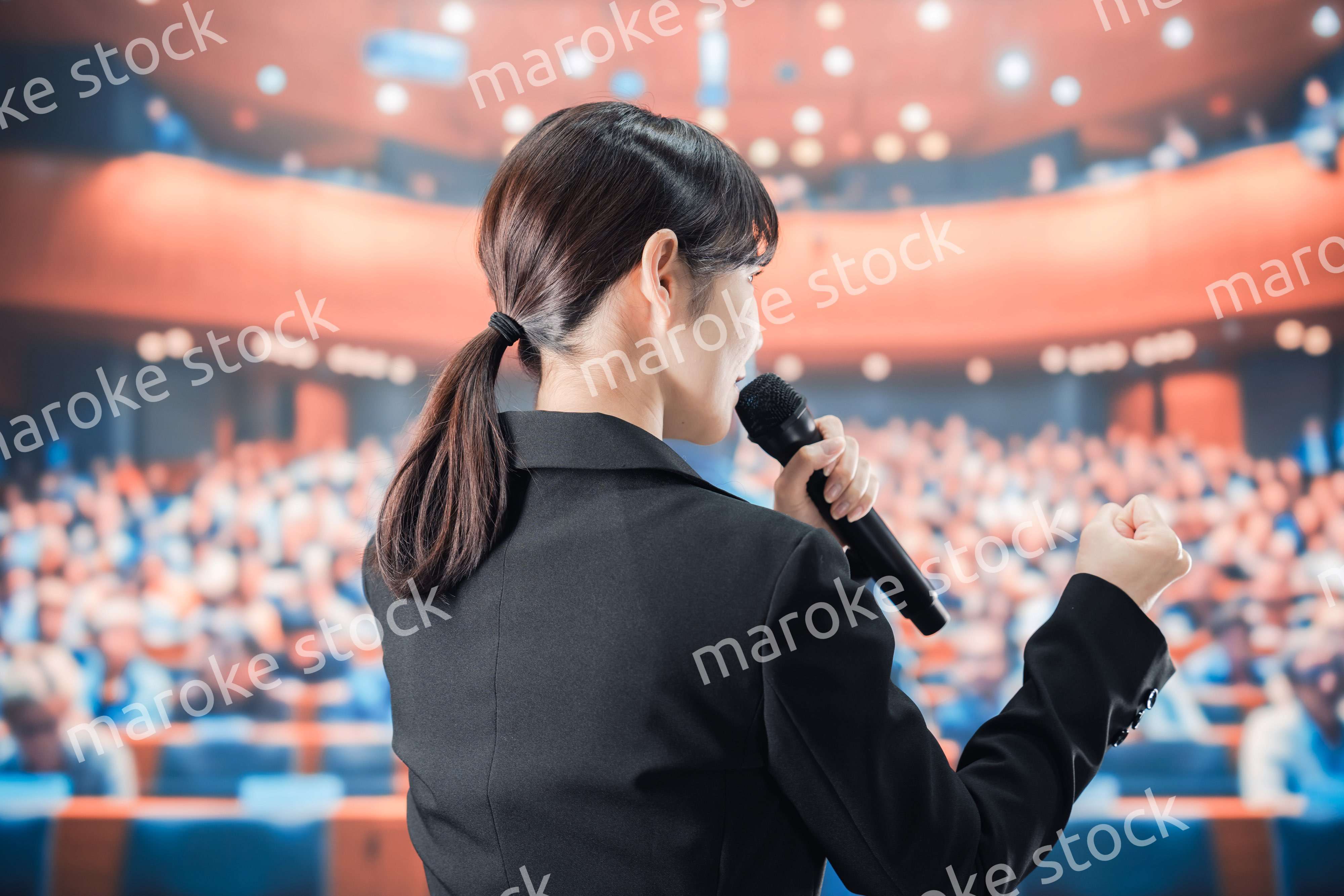大勢の前でマイクで話す女性