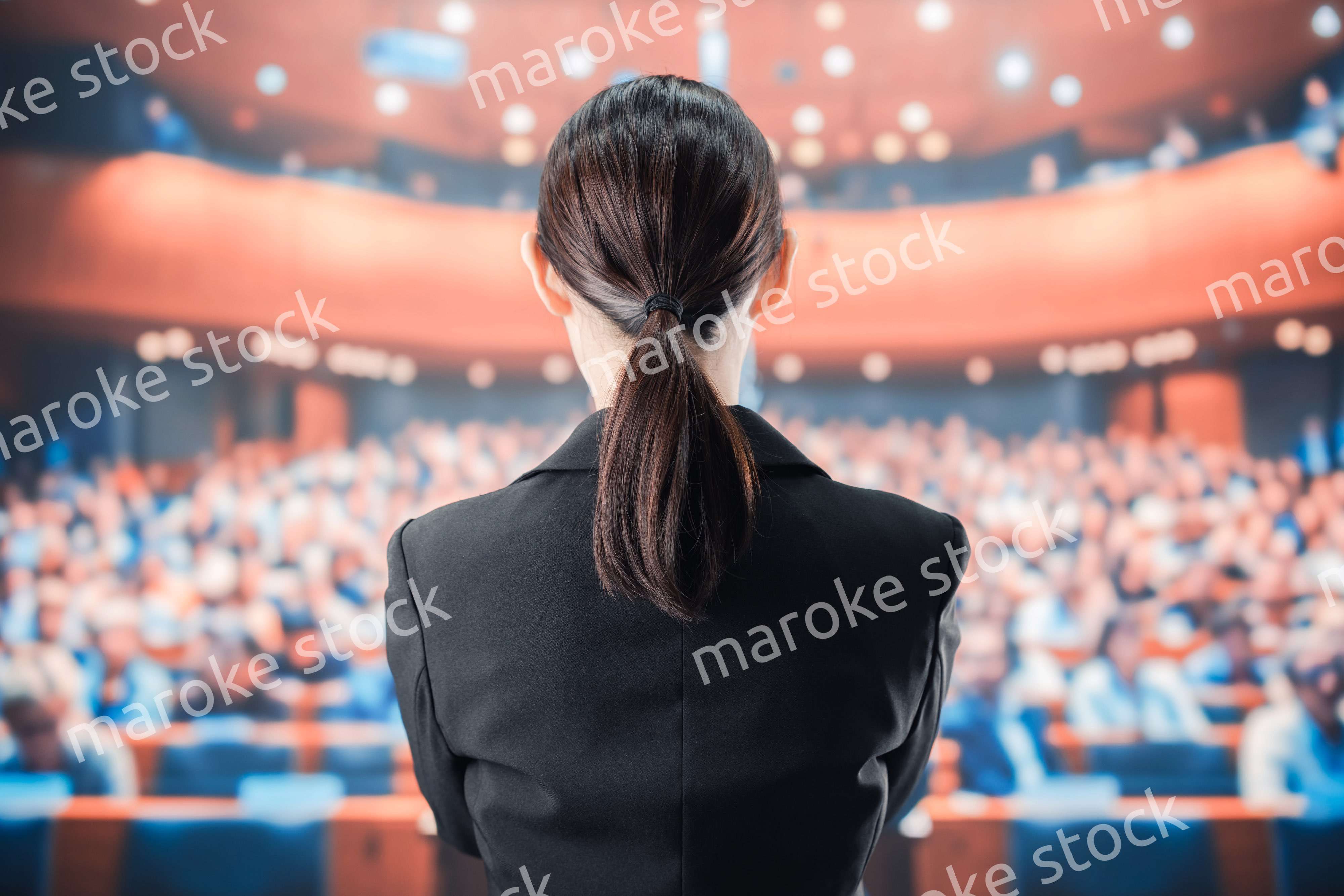 大勢の前でマイクで話す女性