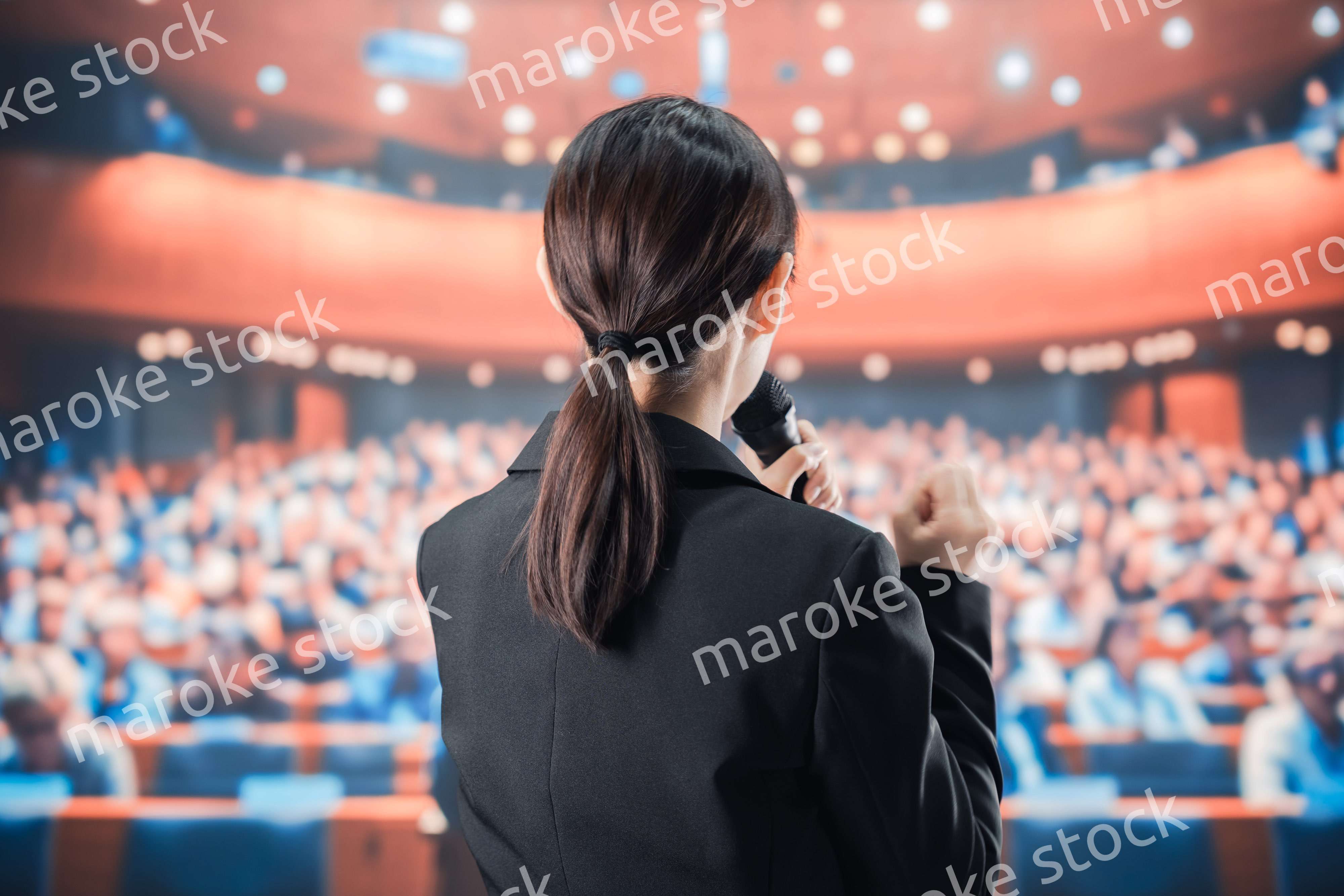 大勢の前でマイクで話す女性