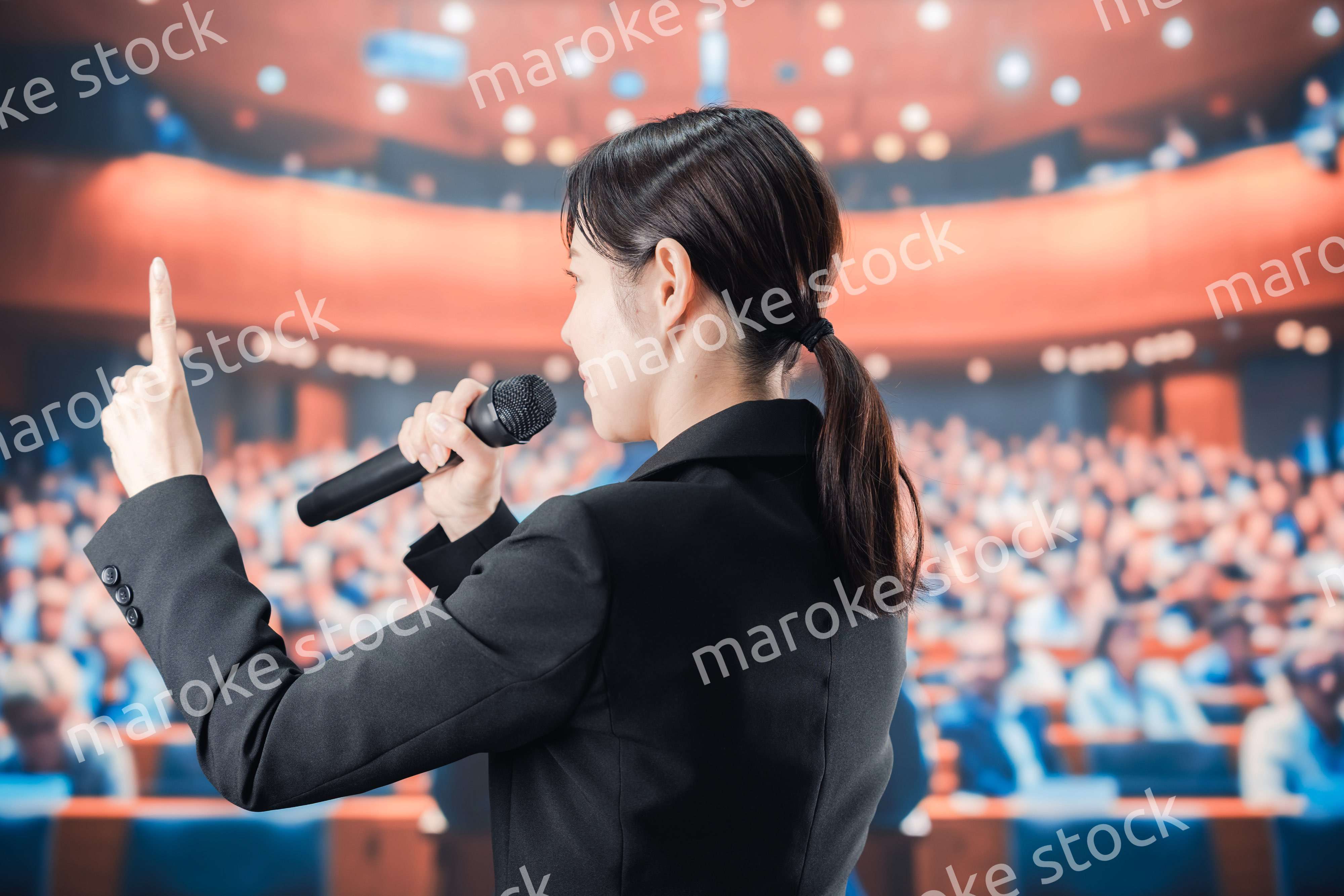 大勢の前でマイクで話す女性