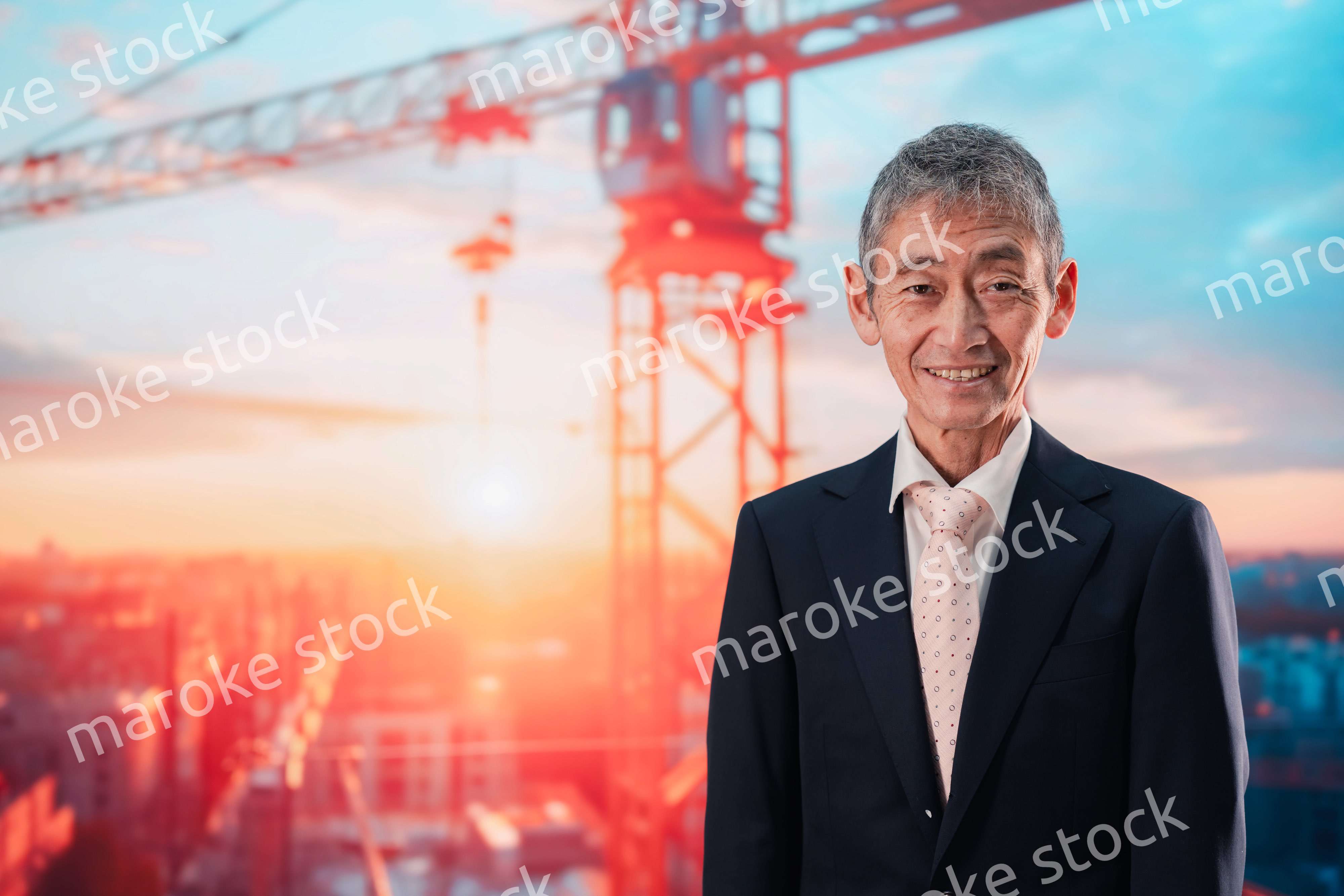 タワークレーンの前に立つスーツ姿の男性ビジネスマン