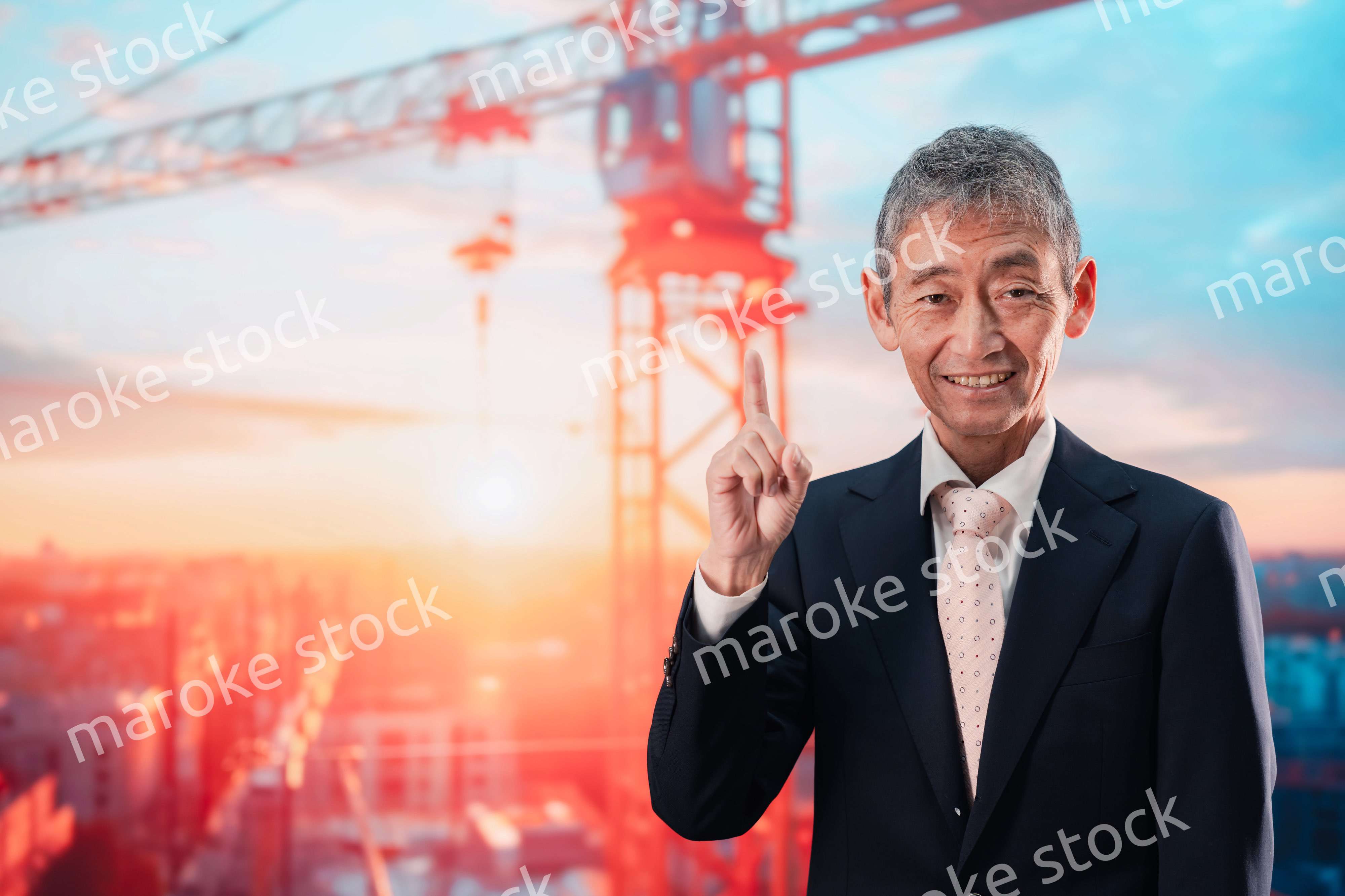 タワークレーンの前に立つスーツ姿の男性ビジネスマン