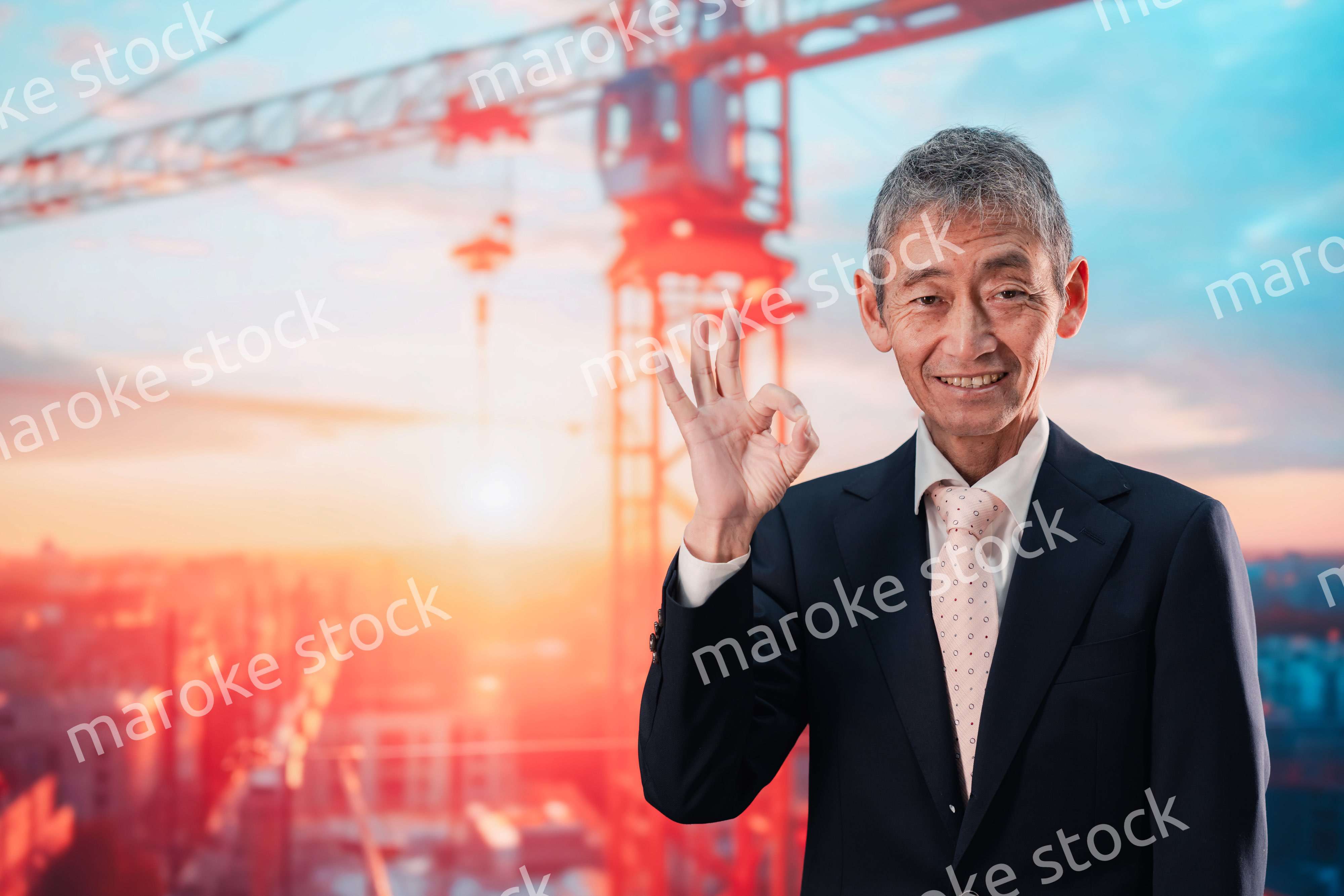 タワークレーンの前に立つスーツ姿の男性ビジネスマン