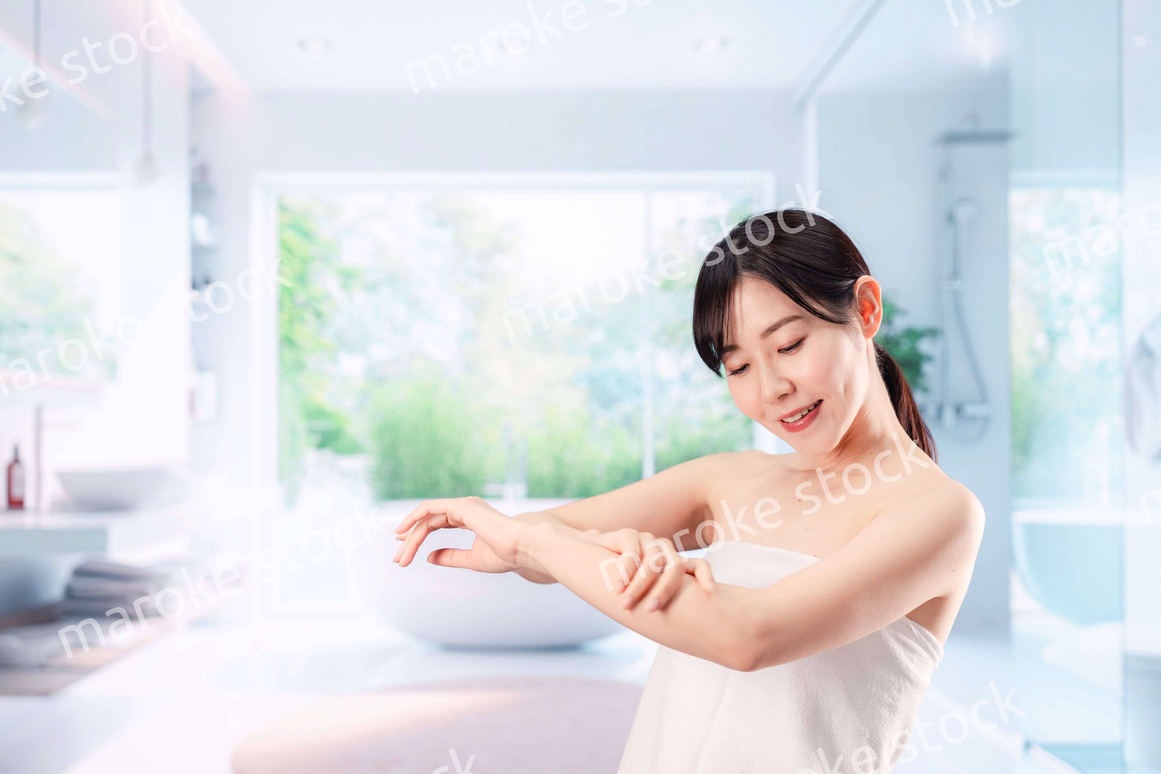 バスルームでボディケアをする若い女性
