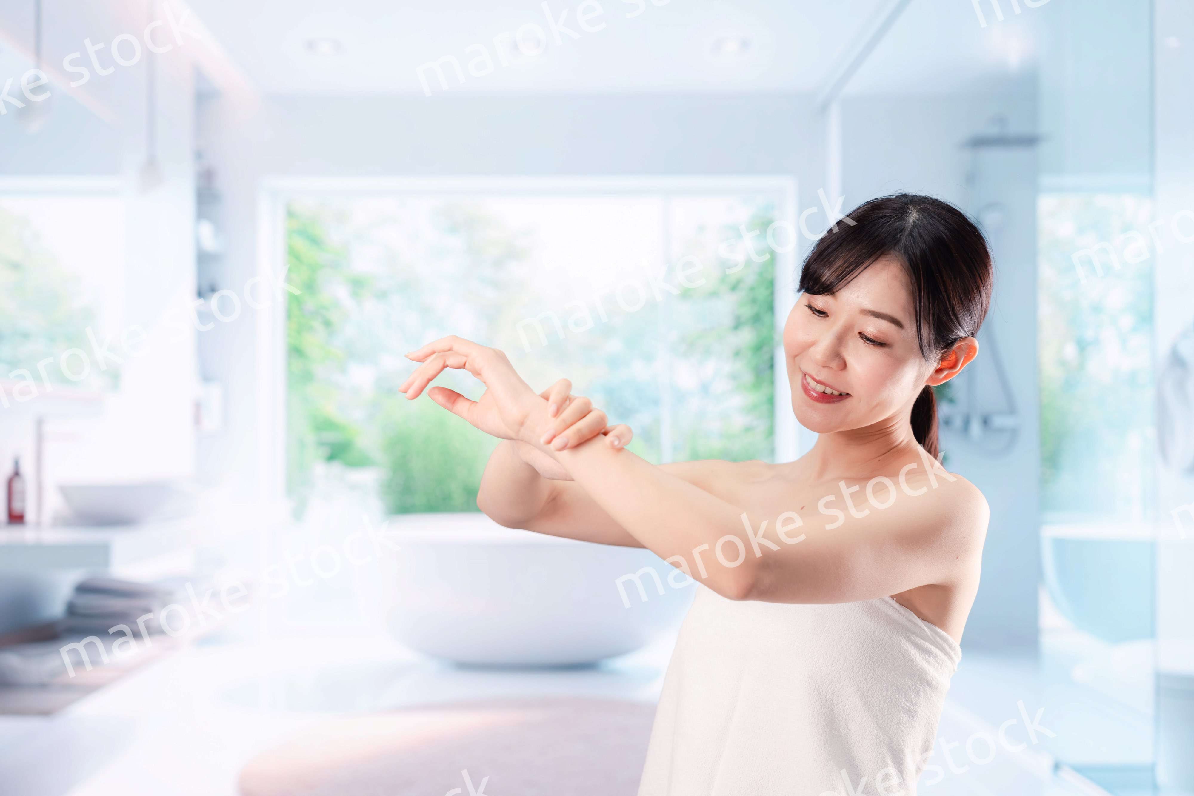 バスルームでボディケアをする若い女性